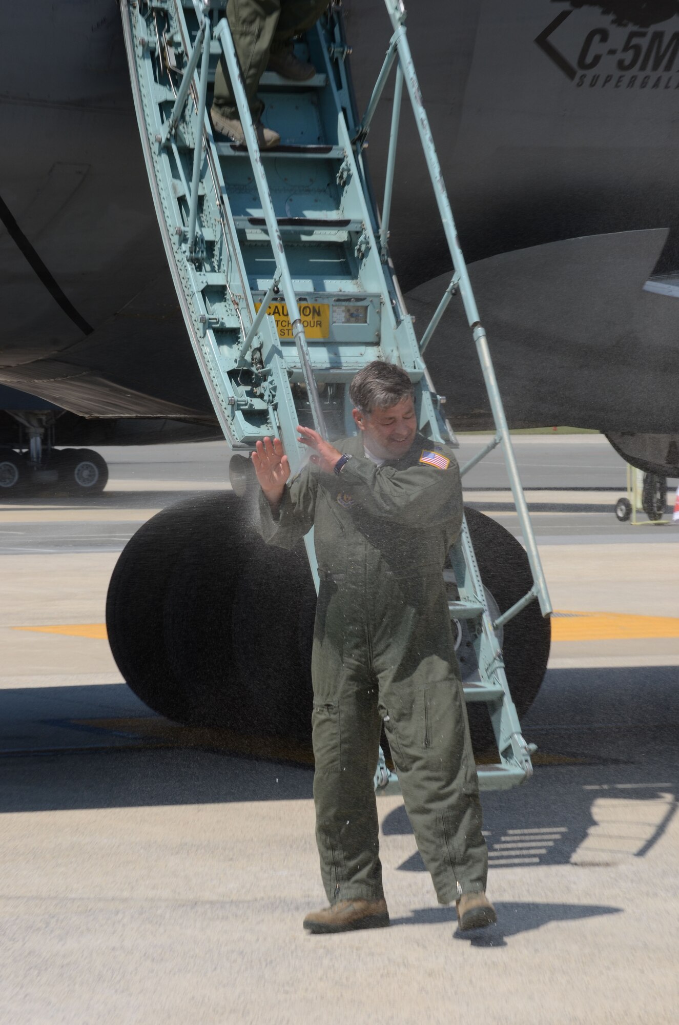 Lt. Col. Chris Cote, 512th Operations Support Squadron, shields his face from the traditional showering of water following a flier''s final flight Aug. 26, 2015, on Dover Air Force Base, Del. Cote landed the C-5M Galaxy for the last time after flying aircraft for the Air Force for 35 years. (U.S. Air Force photo/Master Sgt. Joei Callahan)