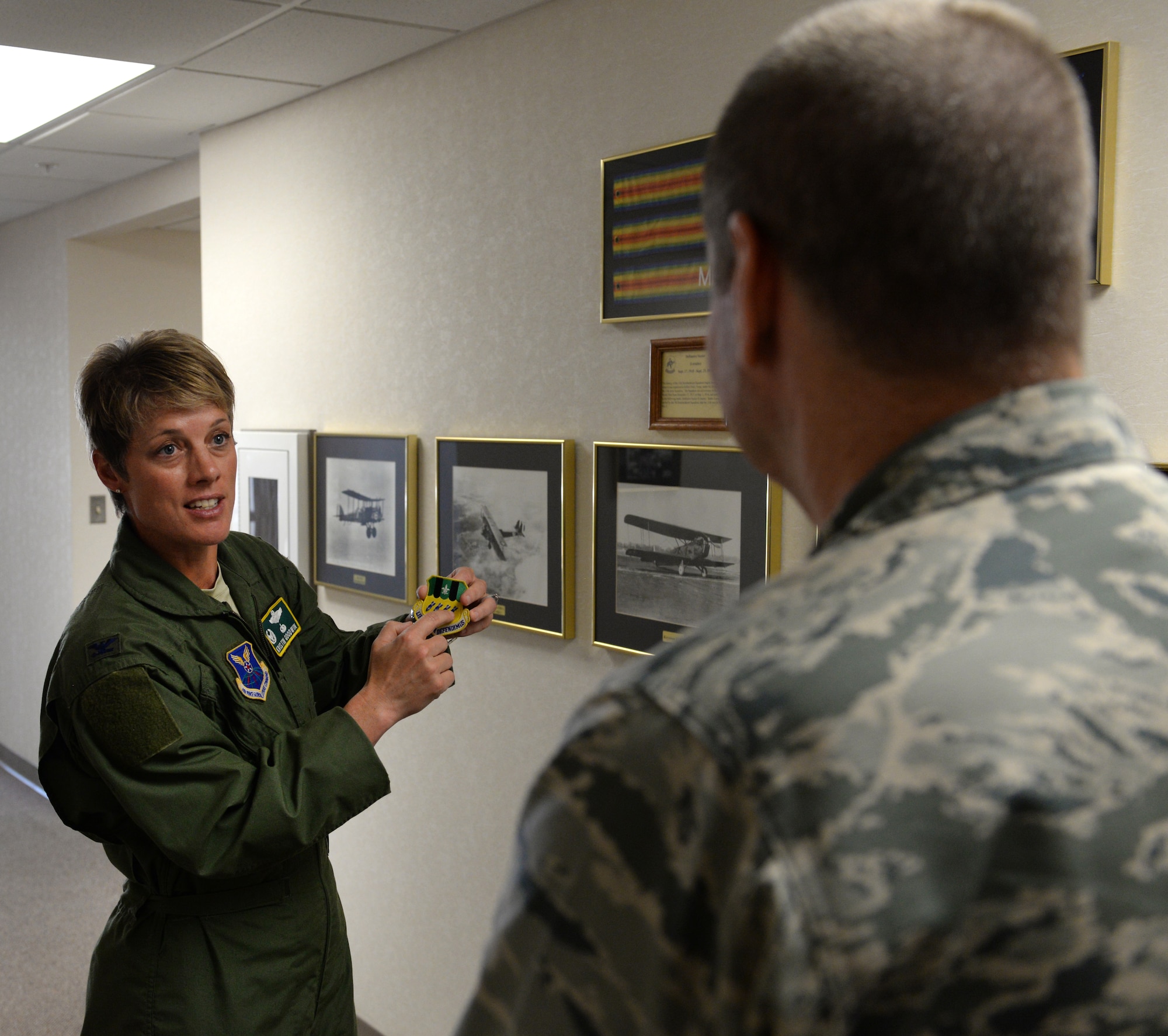 Col. Kristin Goodwin, 2nd Bomb Wing commander, describes the origin of the wing’s emblem patch to Gen. Robin Rand, Air Force Global Strike Command commander, at Barksdale Air Force Base, La., Aug. 27, 2015. The emblem reflects a proud heritage almost as old as American air power. In the shape of an Air Force shield, the emblem is divided at the top into five perpendicular stripes. The colors of the stripes, black and primitive green, are those that the wing bore as part of the Army Air Service during World War I. The three primitive green stripes represent the three major offensives in which the wing participated during that war: St. Mihiel, Lorraine and Meuse-Argonne. The white fleur de lis at the top symbolizes France, the theater of operations for the wing's World War I achievements. The lower portion of the shield is in Air Force golden yellow, charged with four aerial bombs in ultramarine blue, not only representing the original four combatant squadrons assigned during World War I, but also suggesting the unit's present mission as a heavy bombardment wing of Air Force Global Strike Command. (U.S. Air Force photo/Airman 1st Class Curt Beach)