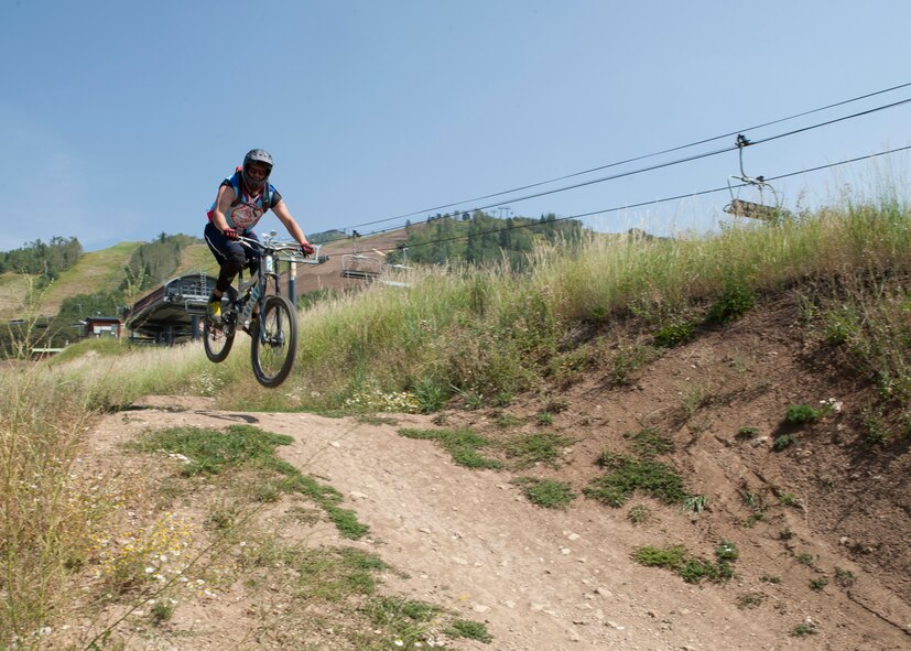 Staff Sgt. Dylan Haley, 90th Munitions Squadron, jumps a tabletop dirt mound at a bike park in Steamboat Springs, Colo., Aug. 29, 2015. The bike park is situated on Mount Werner in Routt National Park. (U.S. Air Force photo by Lan Kim)