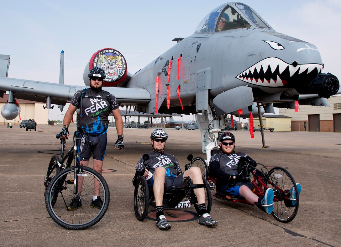 Jarrod Smith, (left), Clay Jacobs, (middle), and Christopher Freeman, (right), take a break at a rest stop at Sheppard Air Force Base, Texas, during the Hotter’N Hell 100 bike race Aug. 29  2015. Freeman is a veteran who was paralyzed from the waist down after a car accident in 2010. He has participated in three Hotter’N Hell rides since the accident to share his story of resiliency with other riders, and observers along the route. (U.S. Air Force photo by Danny Webb/Released)
