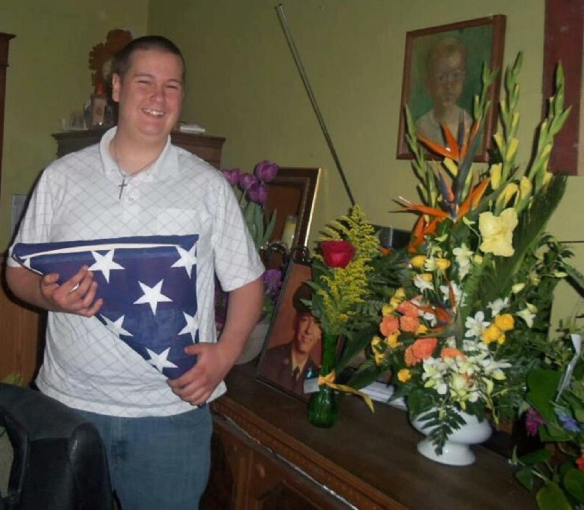 U.S. Air Force Airman 1st Class Daniel Meyer, 55th Aircraft Maintenance Squadron, holds an American flag and stands next to a picture of his father when he was in the Air Force. Meyer, lost more than 100 pounds in order to become an Airman and follow in his father’s shoes. (Courtesy photo)