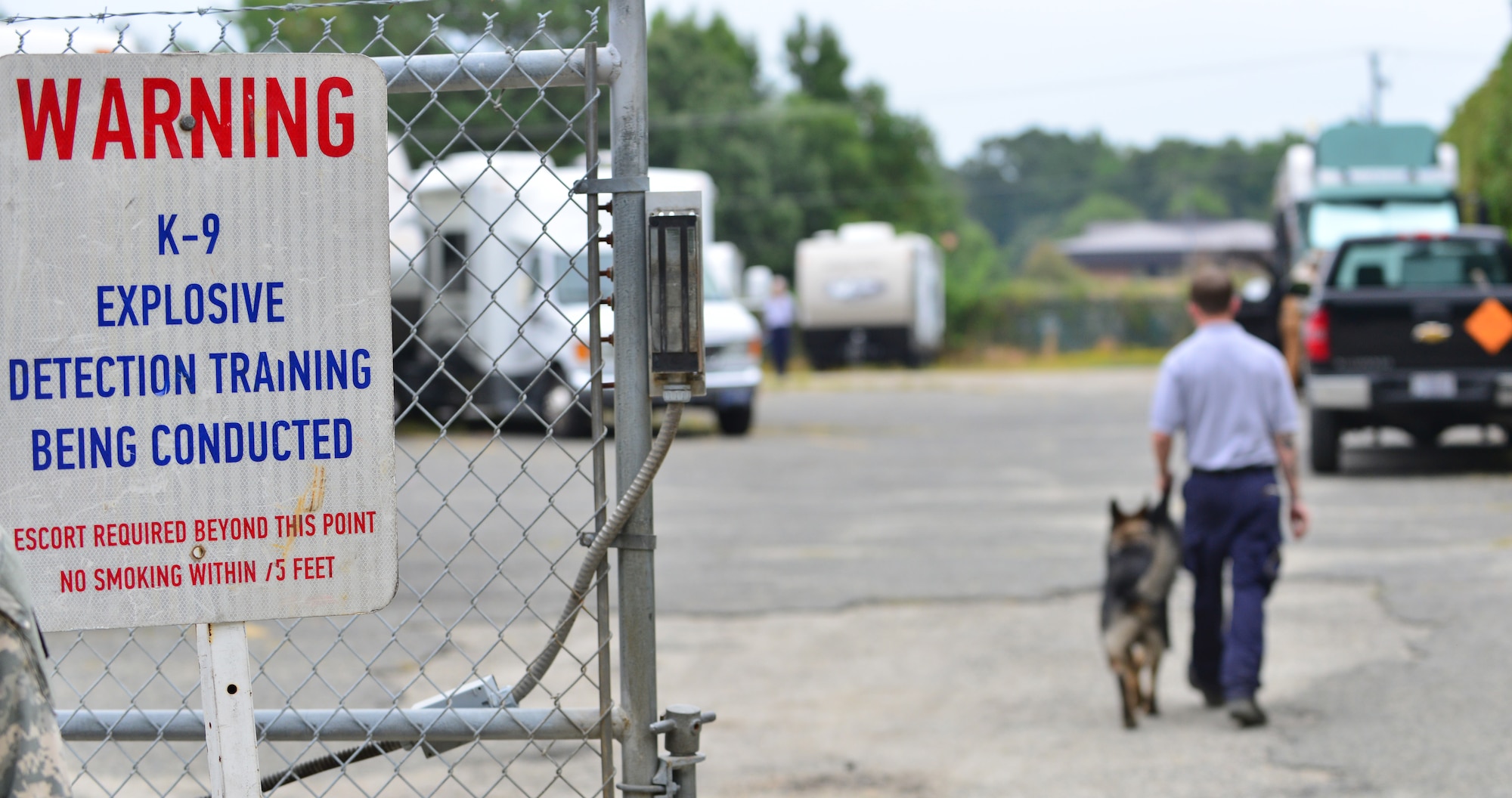 Cody Morris, Explosive Countermeasures International explosives canine handler, walks Orion, explosives detection dog, to a detection training site at Fort Eustis, Va., Aug. 31, 2015. The canines and handlers went through several detection sites where they were trained to find simulated explosive threats during a week-long certification course. (U.S. Air Force photo by Staff Sgt. Natasha Stannard/Released)