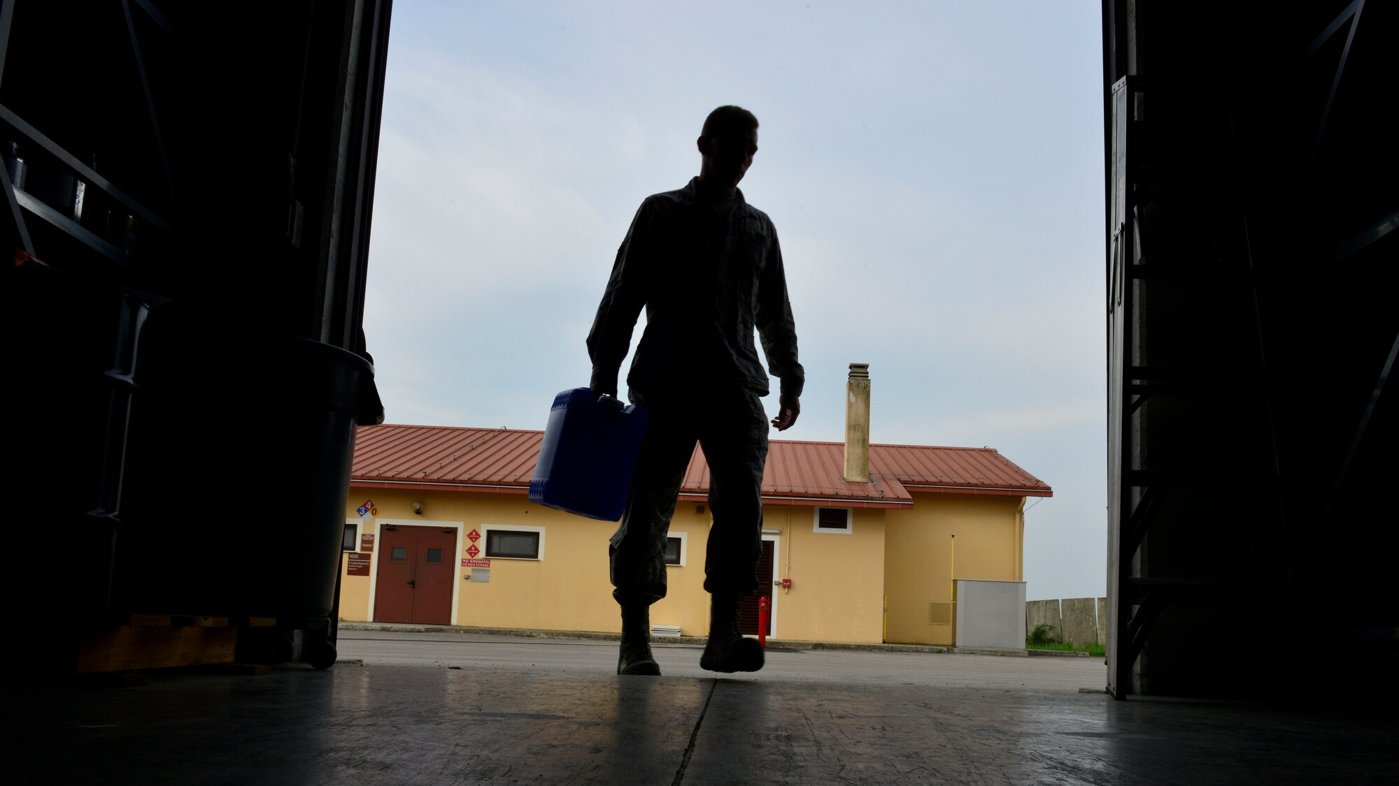 U.S. Air Force Airman 1st Class Kevin Story, 31st Logistics Readiness Squadron Hazardous Material Supply journeyman, carries a container of de-mineralized water into a HAZMAT warehouse, Sept. 2, 2015, at Aviano Air Base, Italy. Corrosive and flammable materials are stored in secure HAZMAT warehouses until they are picked up. (U.S. Air Force photo by Airman 1st Class Cary Smith/Released)