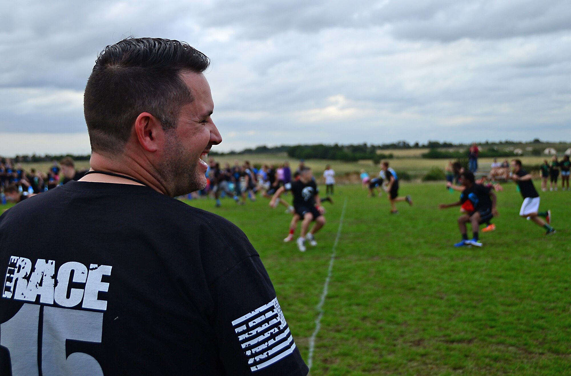 Dale Mace, Club Beyond associate staff and “The Race” creator and director, observes middle and high school students participating in a competitive field game at Royal Air Force Lakenheath, England, Aug. 3, 2015. The chapel sponsored event, “The RACE,” was designed to contribute to family readiness by helping students interact with each other and help socially prepare them for the upcoming school year. (U.S. Air Force photo by Senior Airman Erin O’Shea/Released)  