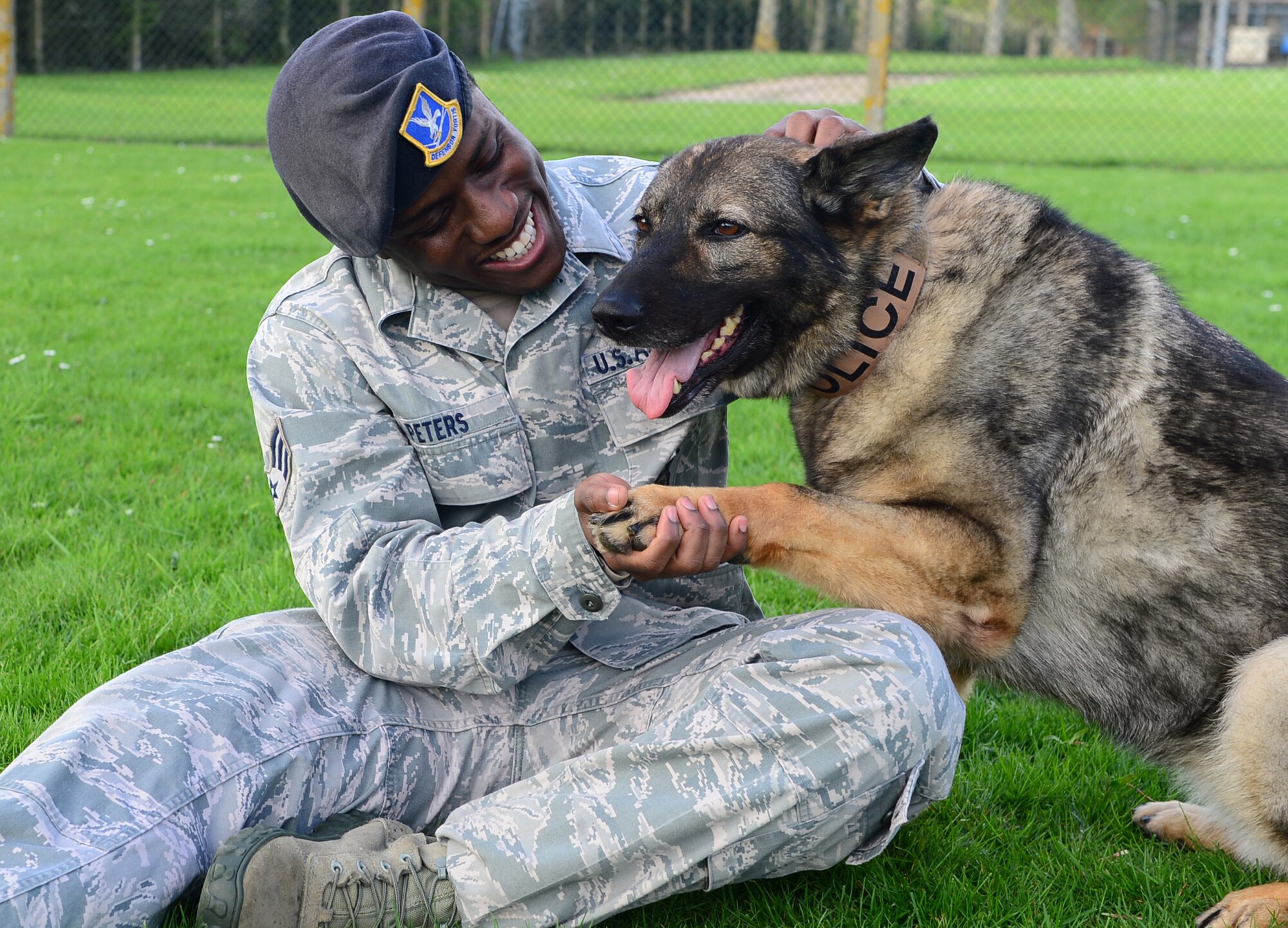 Then Senior Airman Anthony Peters, 48th Security Forces Squadron military working dog handler, praises MWD Gina after completing an obedience course at Royal Air Force Feltwell, England, April 9, 2014. MWD handlers are responsible for keeping their partners trained in techniques to include bite work and detection for drugs or explosives, as well as maintaining a healthy relationship. (U.S. Air Force photo by Senior Airman Dawn M. Weber/Released)