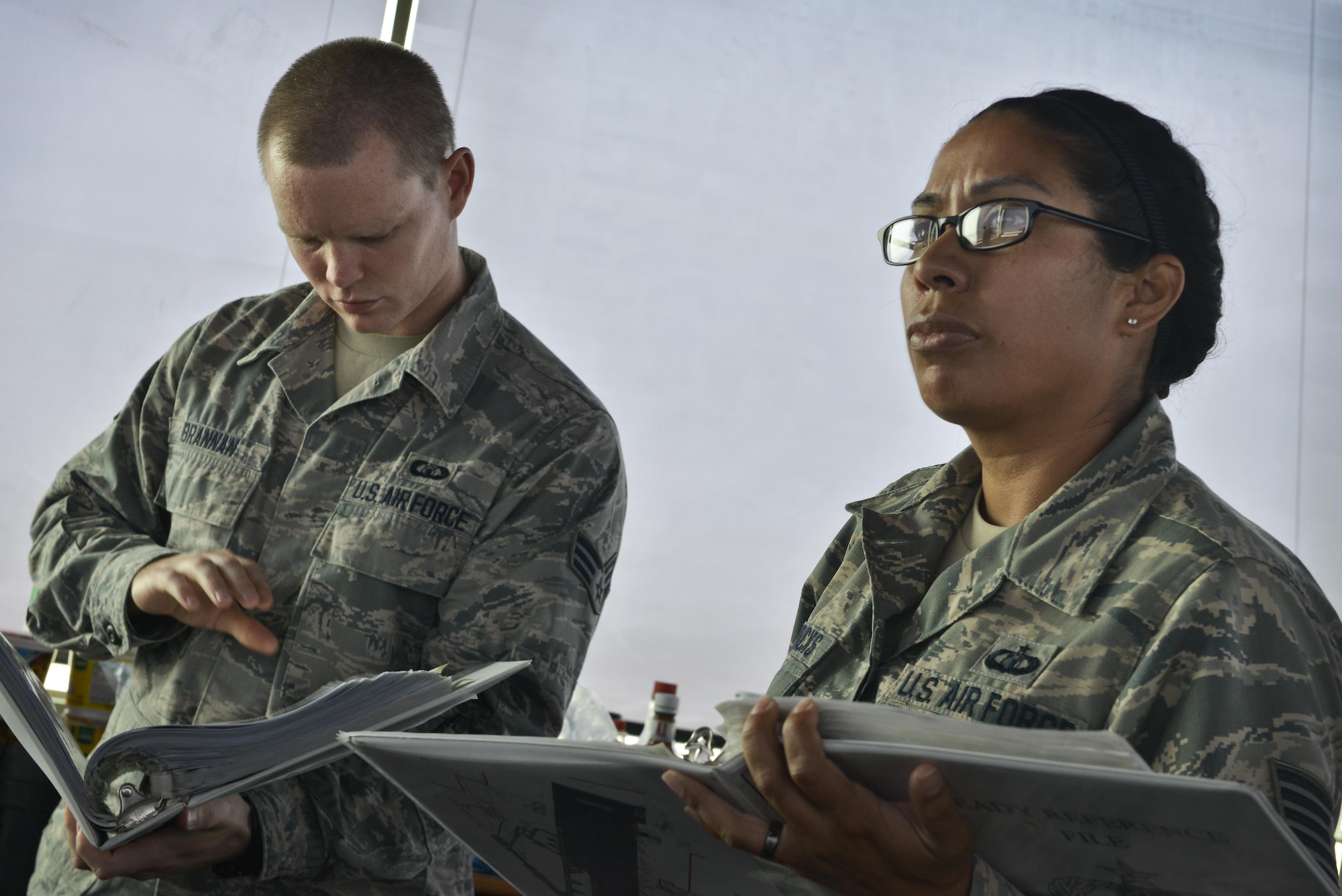 Senior Airman Dustin Brannan and Tech. Sgt. Kelena Hendricks, 379th Expeditionary Operations Support Squadron air traffic control, review base specific airspace operating instructions September 2, 2015 at Al Udeid Air Base, Qatar. While on shift, airmen of the 379th EOSS ATC review airfield operation regulations to stay current and keep coalition forces safe as aircraft taxi, take off and land. (U.S. Air Force photo/Staff Sgt. Alexandre Montes)