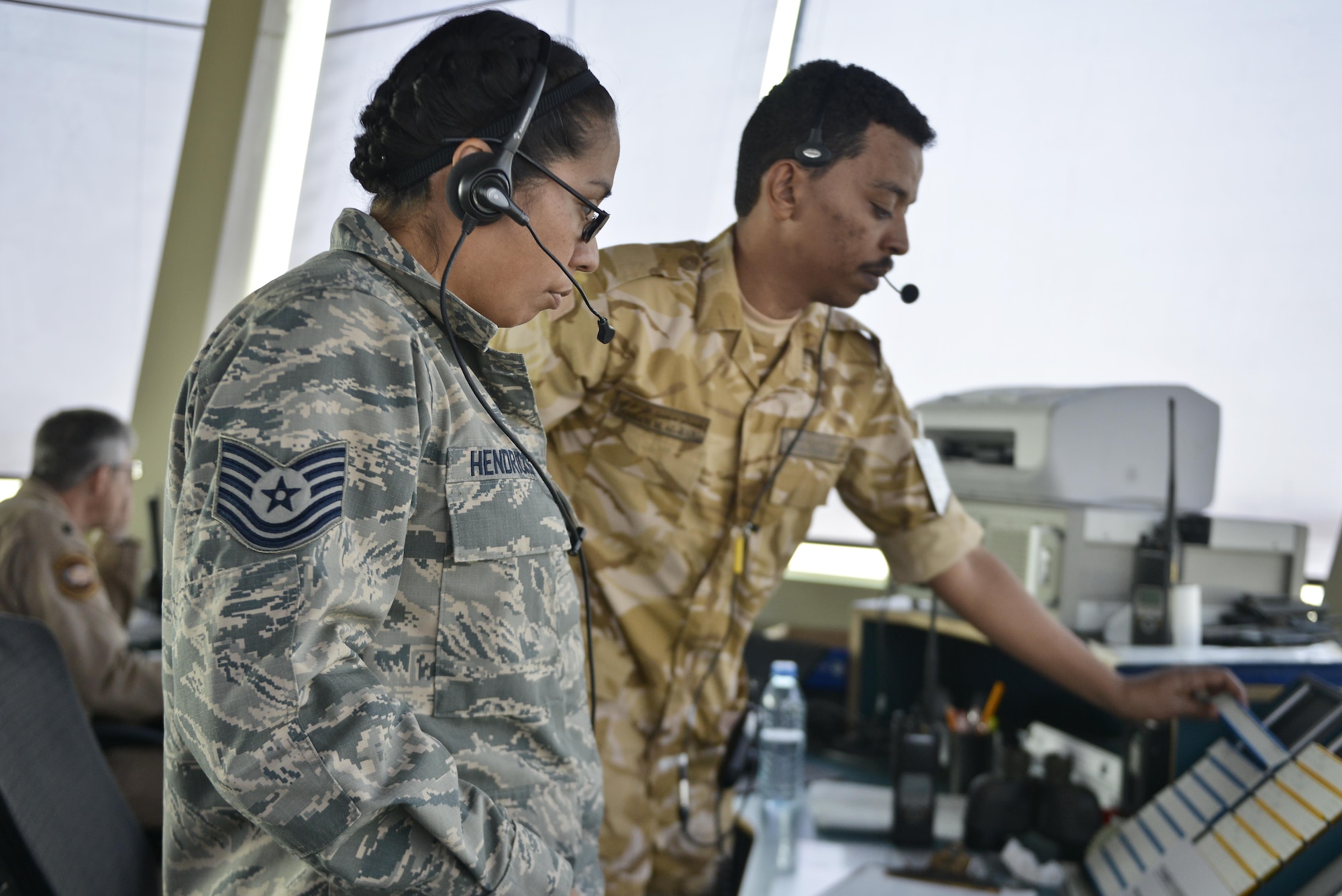 Tech. Sgt. Kelena Hendricks, 379th Expeditionary Operations Support Squadron air traffic controller, receives a changeover brief by a Qatari military member on incoming flight patterns September 2, 2015 at Al Udeid Air Base, Qatar. Airmen of the 379th EOSS ATC work closely with Qatari military ATC conducting airfield operations to support coalition forces deployed here in support of Operation Inherent Resolve and Operation Freedom’s Sentinel. (U.S. Air Force photo/Staff Sgt. Alexandre Montes)