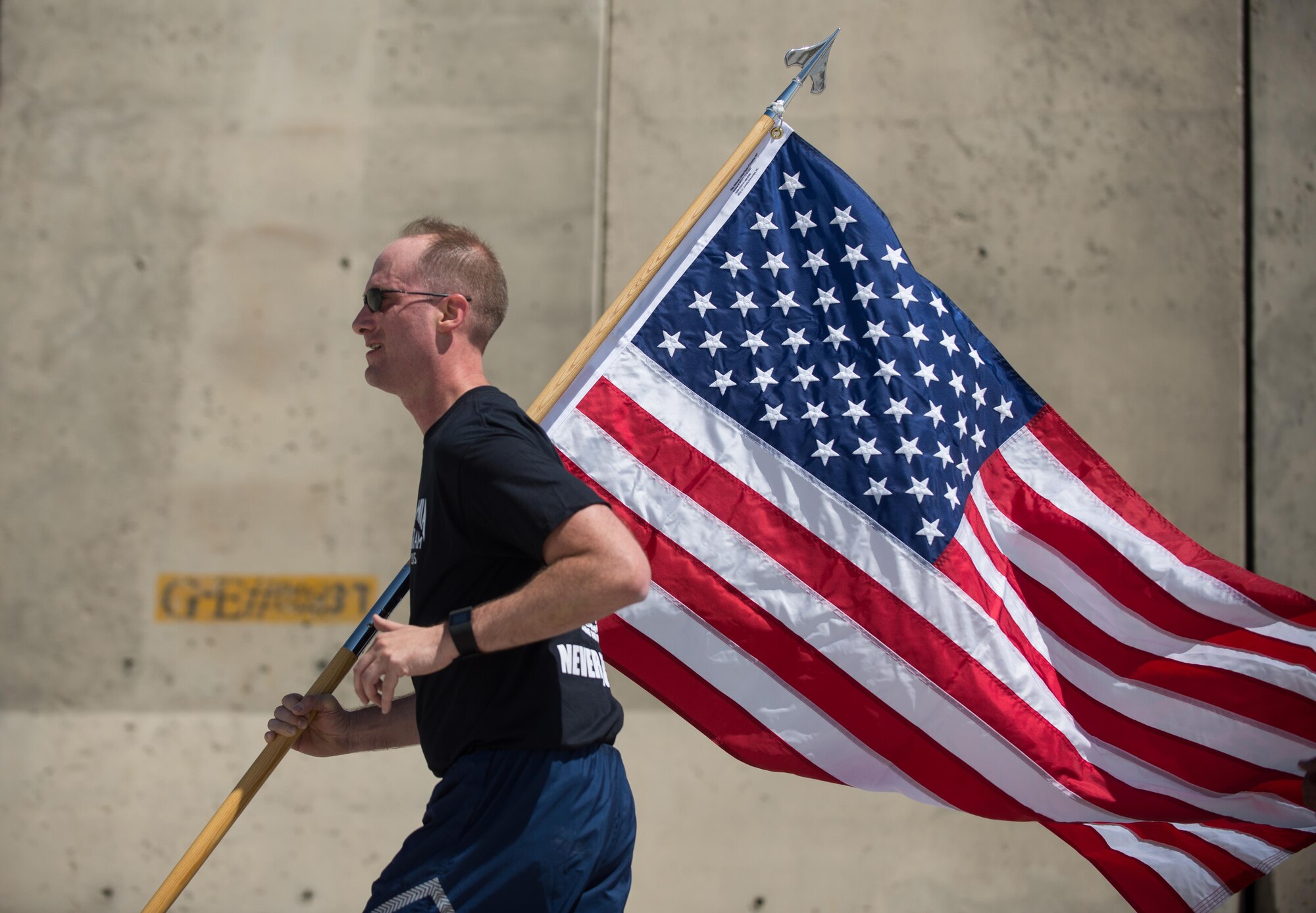 U.S. Air Force Maj. Brian Yates, 455th Air Expeditionary Wing executive to the commander, carries the U.S. flag during the prisoners of war, missing in action run at Bagram Airfield, Afghanistan, Sept. 3, 2015. For 24 straight hours, BAF Service members kept the POW/MIA flag in constant motion in honor of American prisoners of war and those missing in action. (U.S. Air Force photo by Tech. Sgt. Joseph Swafford/Released)