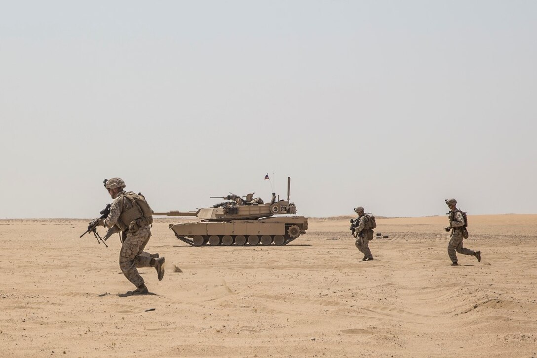 KUWAIT (Aug. 24, 2015) U.S. Marines with Kilo Company, Battalion Landing Team 3rd Battalion, 1st Marine Regiment, 15th Marine Expeditionary Unit (MEU), rush towards enemy targets during mechanized squad attack training. The training focused on the squad’s ability to effectively utilize AAV-7 Amphibious Assault Vehicles and M1A1 Abrams tanks to close with and destroy enemy targets. Elements of the 15th MEU are ashore in Kuwait for sustainment training to maintain and enhance the skills they developed during their pre-deployment training period.  The 15th MEU is embarked with the Essex Amphibious Ready Group and deployed to maintain regional security in the U.S. 5th Fleet area of operations. (U.S. Marine Corps photo by Sgt. Emmanuel Ramos/Released)