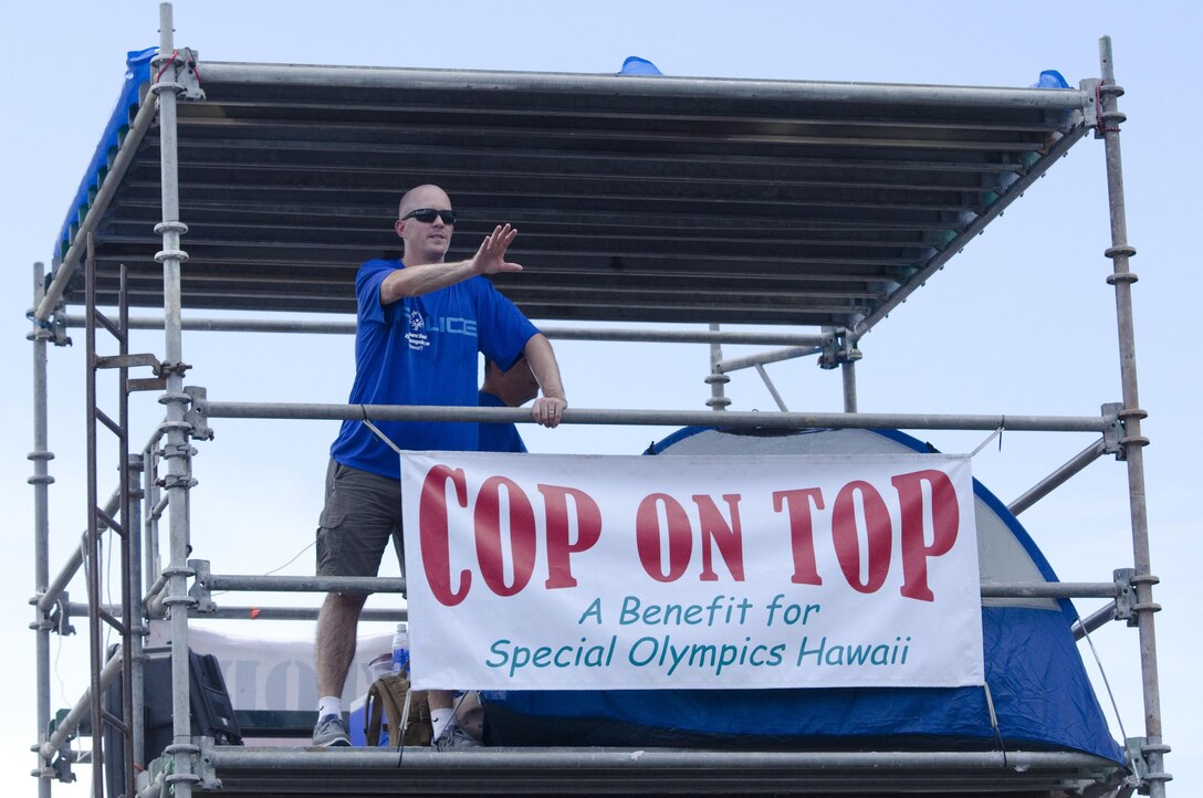 Master Gunnery Sgt. Christopher Benke, the provost sergeant of the Provost Marshal’s Office and a Cascade, Iowa, native, greets patrons during the Cop on Top event at the Kaneohe Bay Shopping Center, Aug. 28, 2015. Service members and civilians from Marine Corps Base Hawaii volunteered at Aikahi and Kaneohe Bay Shopping Centers for the annual fundraiser that supports Special Olympics Hawaii, from Aug. 27 through 29. Volunteering with community service projects such as Special Olympics Hawaii affords the service members an opportunity to interact and strengthen relationships with the local community, allowing the installation to focus on its larger mission of enhancing combat readiness for all operating forces and tenant organizations. (U.S. Marine Corps photo by Kristen Wong/Released) 