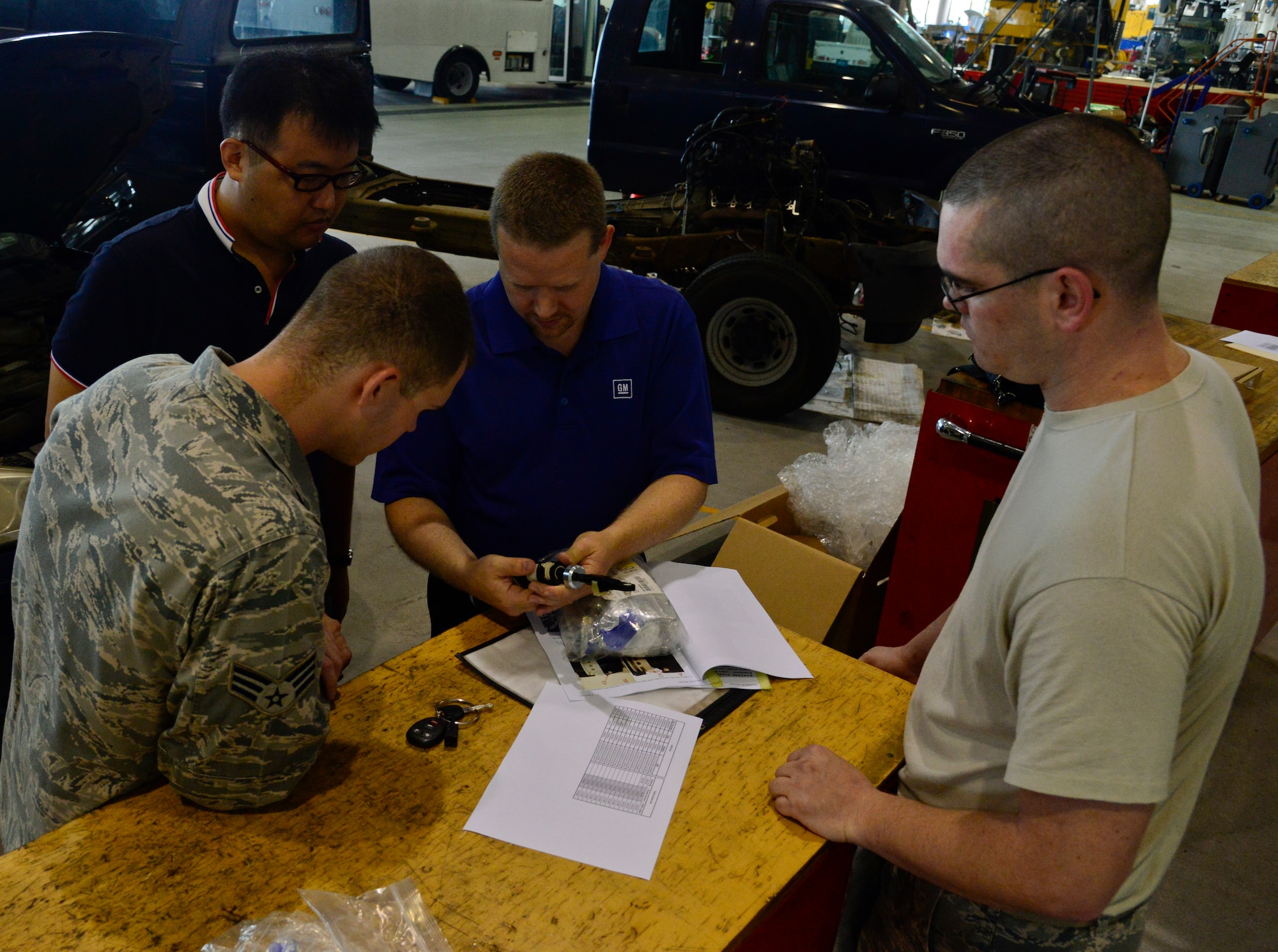 Ryan Brown, vehicle service representative, shows vehicle maintainers from the 51st Logistics Readiness Squadron, how to properly repair a defective part on Osan Air Base, Republic of Korea, Sept. 3, 2015. The Airmen will correct defective parts on 14 sedans, saving more than $300K in vehicle replacements. (U.S. Air Force photo/Senior Airman Kristin High)
