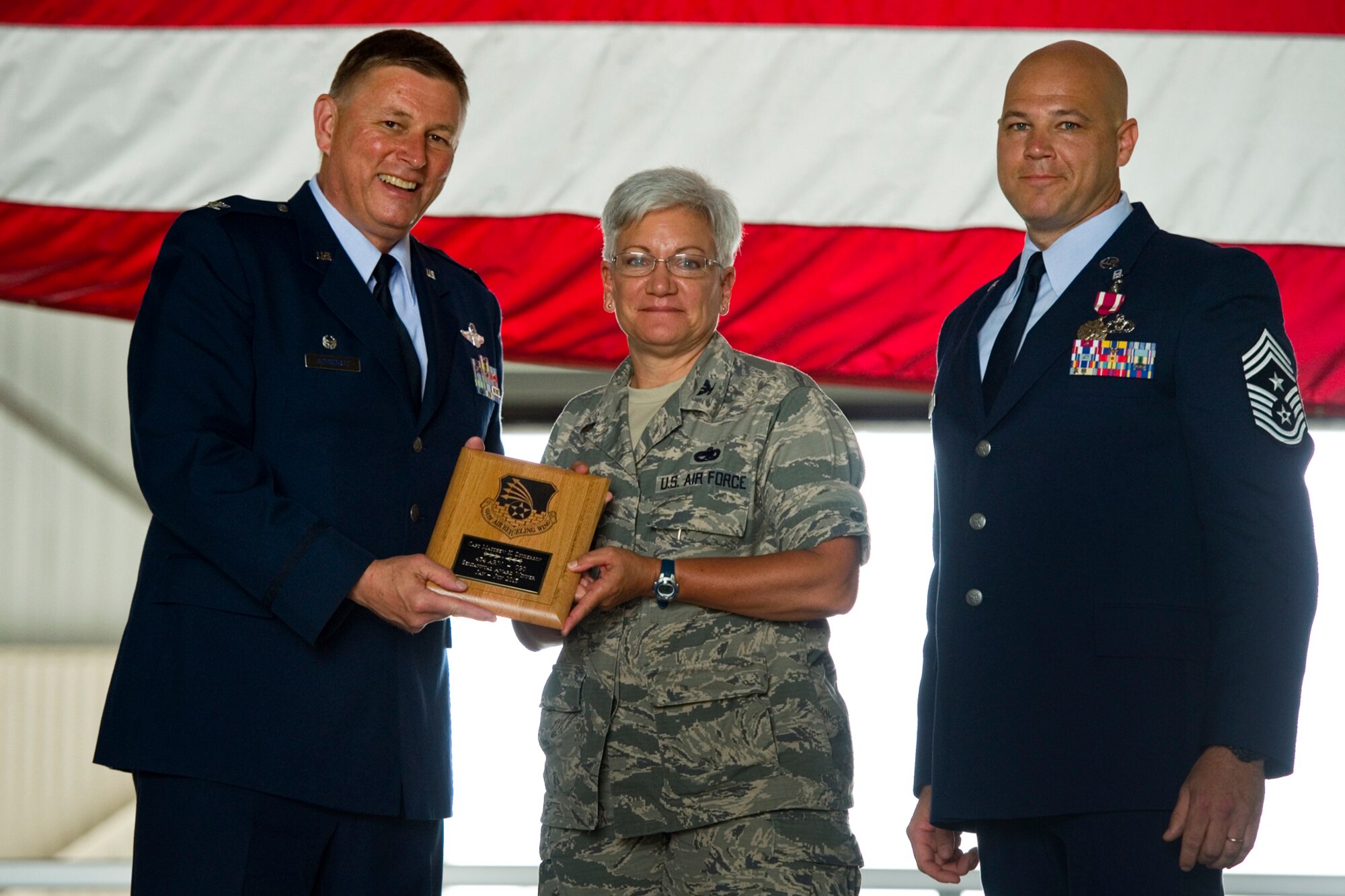 Col. Doug Schwartz, 434th Air Refueling Wing commander, left, presents Col. Anna Schulte, 434th Maintenance Group commander, with a plaque for Capt. Matthew Dickerson, 434th Maintenance Squadron  AMU officer in charge, after he was named top 434th ARW company grade officer for the first half of 2015 during a commander's call at Grissom Air Reserve Base, Ind., Aug. 9, 2015. Twice a year Grissom recognizes the best of the best with this award program. (U.S. Air Force photo/Senior Airman Jami Lancette)