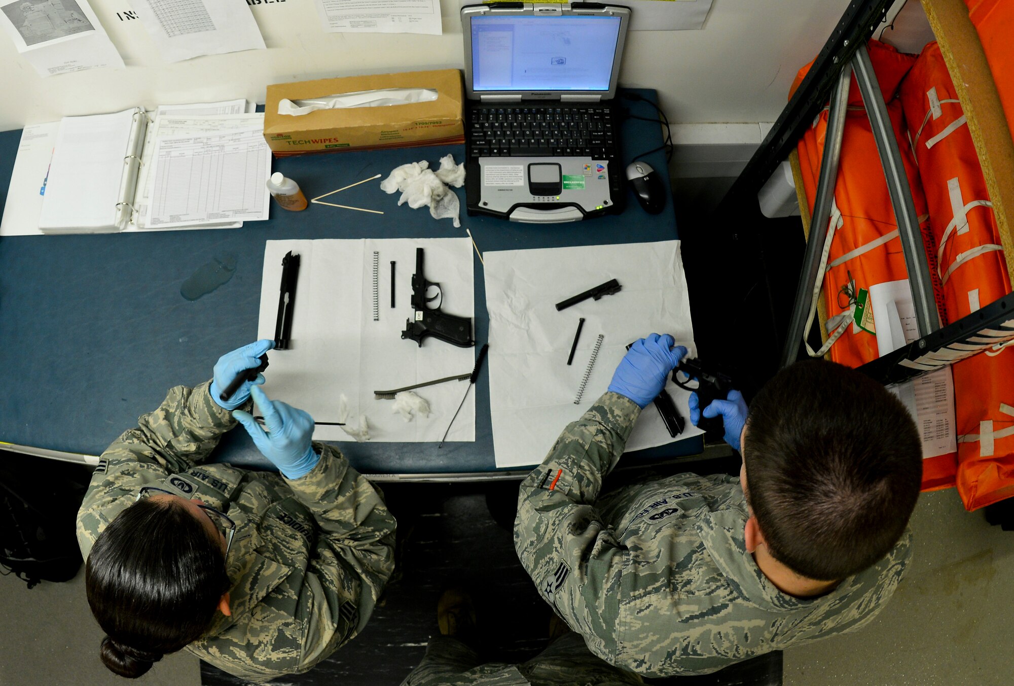 U.S. Air Force Senior Airman Alexandria Delguidice, left, and U.S. Air Force Senior Airman William Ennis, both, 100th Operations Support Squadron Aircraft Flight Equipment journeymen, disassemble M-9 pistols Sept. 3, 2015, on RAF Mildenhall, England. Delguidice and Ennis disassembled and inspected the weapons to ensure they were free of cracks, dips, defects and scratches. (U.S. Air Force photo by Staff Sgt. Micaiah Anthony/Released)