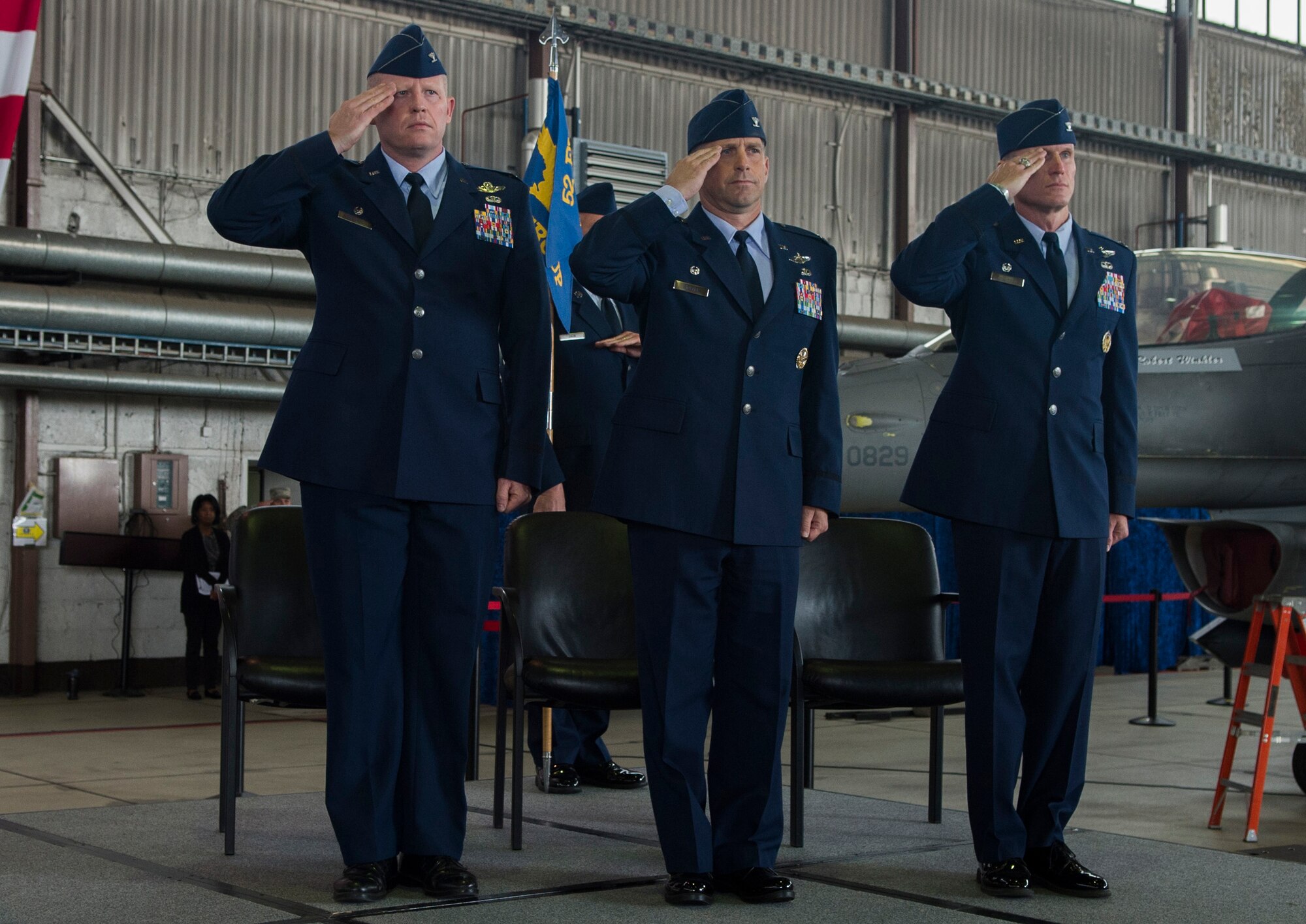 U.S. Air Force Col. Joe McFall, 52nd Fighter Wing commander, left, U.S. Air Force Col. Robert Winkler, former 52nd Operations Group commander, center, and U.S. Air Force Col. Michael Thompson, 52nd OG commander, salute during the singing of the U.S. national anthem at the 52nd OG change of command ceremony in Hangar one on Spangdahlem Air Base, Germany, Sep. 4, 2015. Thompson will serve as the new 52nd OG commander. (U.S. Air Force photo by Airman 1st Class Luke Kitterman/Released)