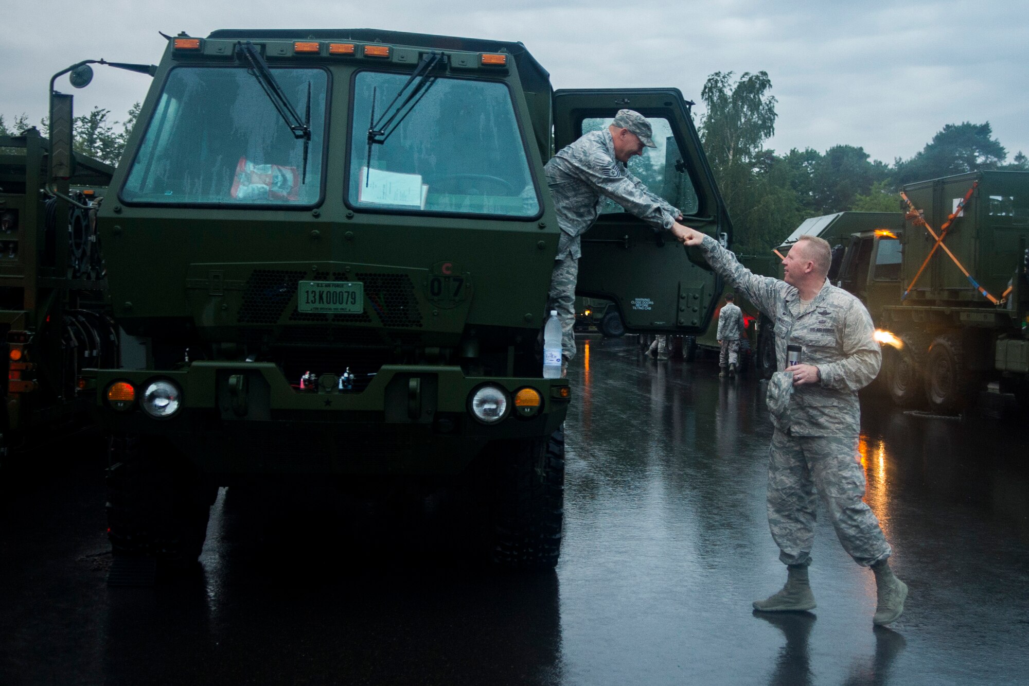 U.S. Air Force Col. Joe McFall, 52nd Fighter Wing commander, right, bumps fists with a 606th Air Control Squadron Airman at Spangdahlem Air Base, Germany, Sep. 1, 2015. McFall, along with other wing leaders, went to support the 606th ACS Airmen before they began convoying to Poland. The convoy was the largest to date, consisting of 121 Airmen, 40 vehicles and two TPS-75 radars. The 606th ACS will set up two operating bases in Poland working to jointly control airspace. (U.S. Air Force photo by Airman 1st Class Luke Kitterman/Released)  
