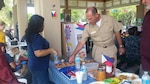 Naval Air Station Jacksonville, Florida Commander Captain Howard Wanamaker visits Defense Logistics Agency Aviation's display on the Philippines during the base’s Multicultural Fun Day July 22, 2015. DLA Aviation at Jacksonville Sustainment Specialist Leslie Stanley provides the commander with instructions on how to play Sungka, one of the most popular board games in the Philippines.