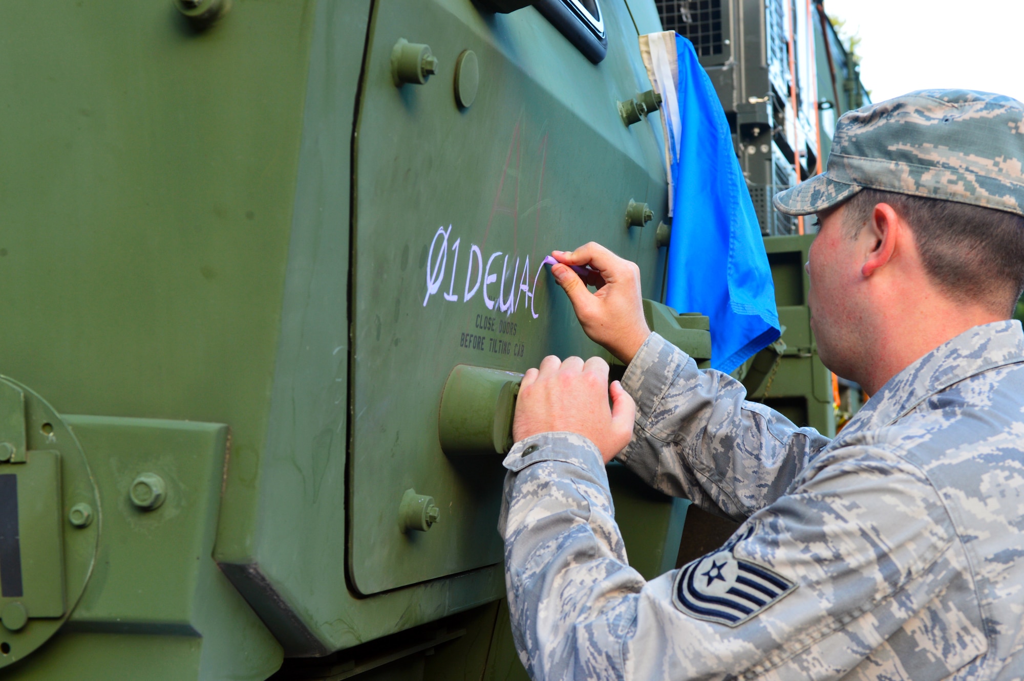 U.S. Air Force Tech. Sgt. Denton Bielinski, 606th Air Control Squadron NCO in charge of power production, marks the daily German road clearance authorization number on his truck in preparation to convoy from Spangdahlem Air Base, Germany, to Poland Sept. 2, 2015. Airmen marked the vehicles in the convoy their road clearance authorization numbers to show they were allowed to travel on German roadways. The Airmen will participate in Aviation Detachment Rotation 15-4, hosted by the U.S. Air Force Aviation Detachment stationed at Łask Air Base, Poland, as part of the latest training exercise designed to strengthen the interoperability of NATO allies. (U.S. Air Force photo by 2nd Lt. Meredith Mulvihill/Released)