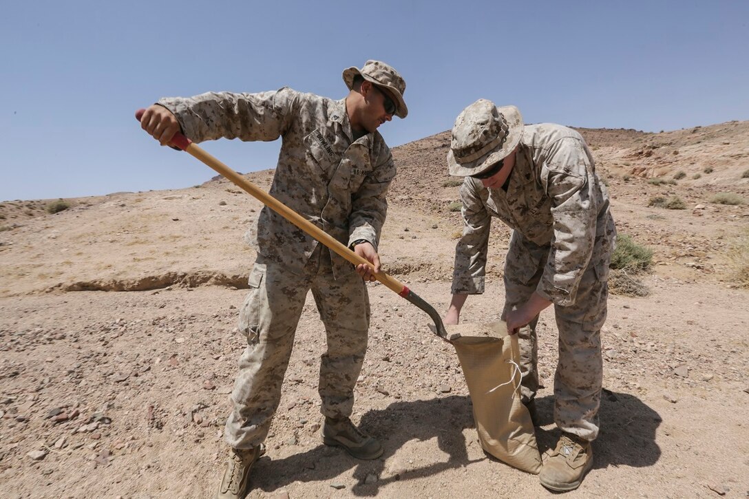 SOUTHWEST ASIA (Aug. 24, 2015)  U.S. Marine Cpl. William Bowling, left, and Cpl. Tyler Thompson, right, fill sand bags to fortify their position during a bi-lateral training exercise. Bowling is a radio operator and Thompson is a forward observer with India Company, Battalion Landing Team 3rd Battalion, 1st Marine Regiment, 15th Marine Expeditionary Unit.  The 15th MEU, embarked aboard the ships of the Essex Amphibious Ready Group, is a forward-deployed, flexible sea-based MAGTF capable of engaging with regional partners and maintaining regional security. (U.S. Marine Corps photo by Sgt. Jamean Berry/Released)