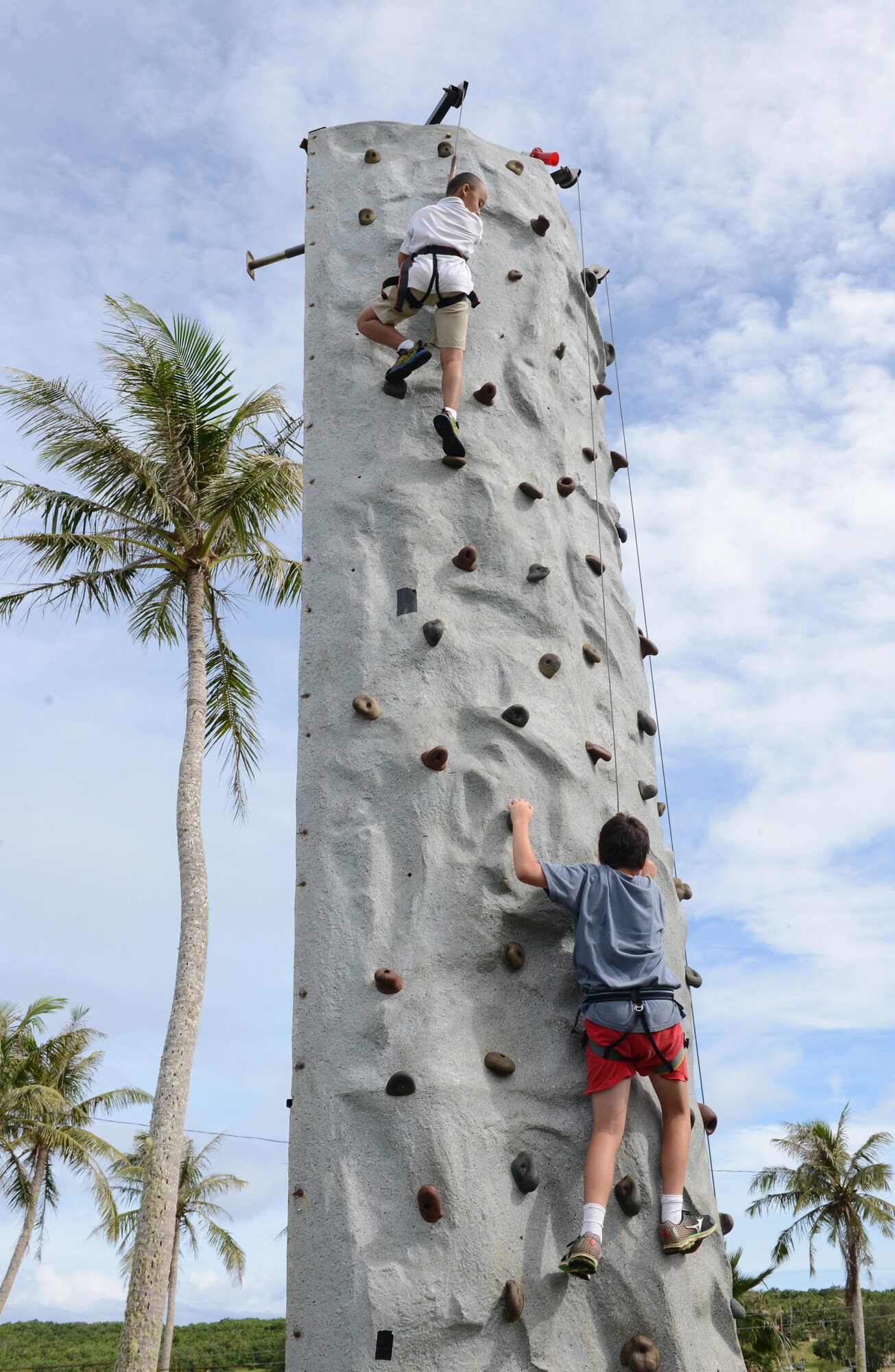 Andersen family members tackle a rock climbing wall at the Labor Day Bash Sept. 4, 2015, on Andersen Air Force Base, Guam. The event included family friendly activities such as rock wall climbing, zip lining, carabao rides, dance-off contests and a Mockingbird Sun concert at the end. (U.S. Air Force photo by Airman 1st Class Arielle Vasquez/Released)