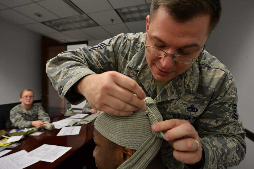 U.S. Air Force Master Sgt. David Hanson, 20th Fighter Wing CVN maintenance manager, bandages the head of an Airman during a self-aid and buddy care course at Shaw Air Force Base, S.C., Sept. 8, 2015. Each year Airmen and Air Force employees must have hands-on SABC training to ensure they have knowledge of the different ways to care for someone during an emergency. (U.S. Air Force photo by Senior Airman Diana M. Cossaboom/Released)