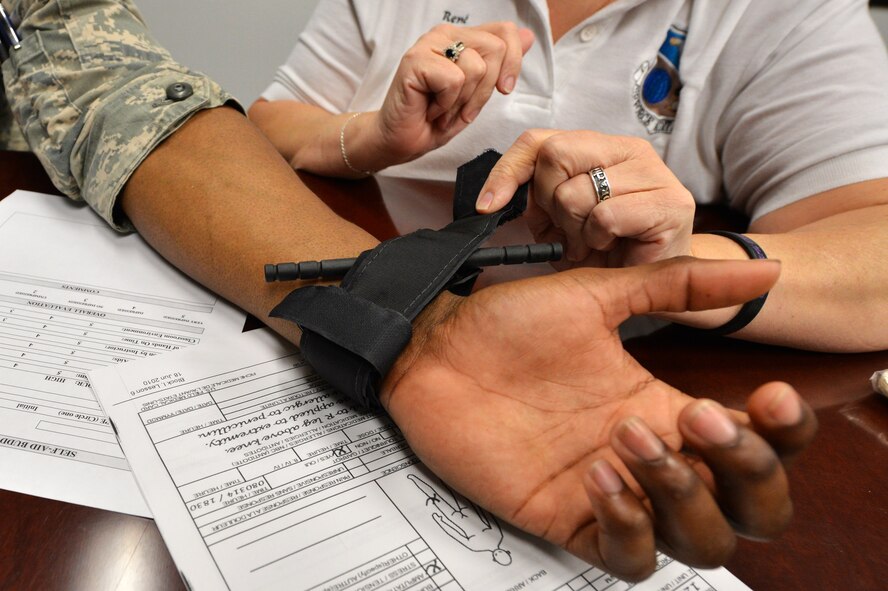 Team Shaw members demonstrate how to apply a tourniquet during a self-aid and buddy care class at Shaw Air Force Base, S.C., Sept. 3, 2015. The class teaches the different types of care including care under fire and tactical field care for the different situations Airmen or Air Force employees may encounter. (U.S. Air Force photo by Senior Airman Diana M. Cossaboom/Released)