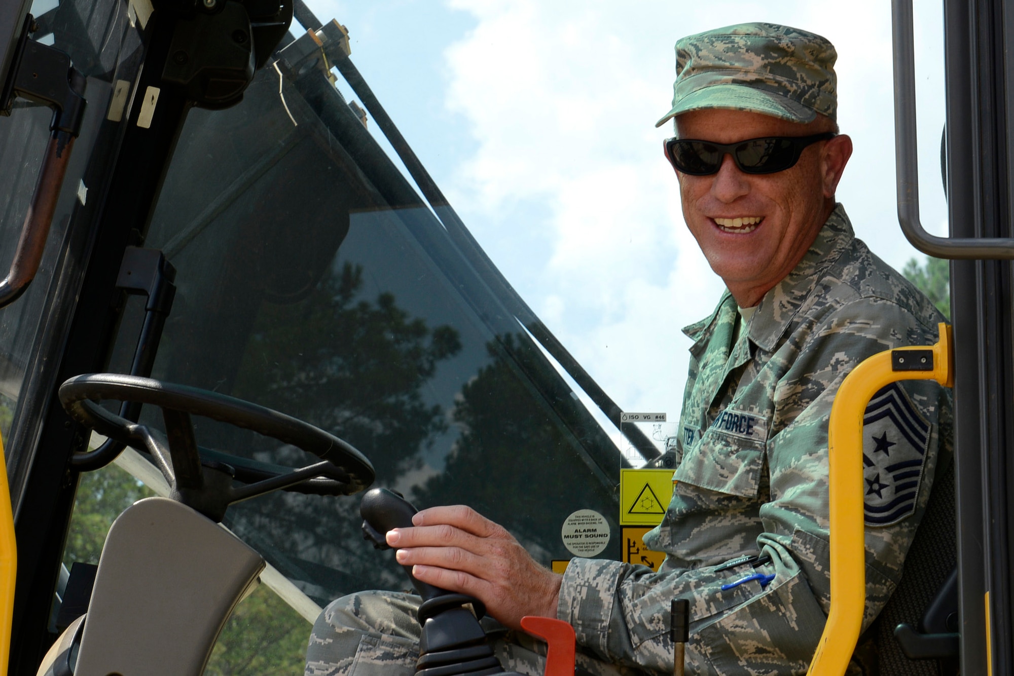 U.S. Air Force Chief Master Sgt. Frank Batten III, the Ninth Air Force command chief takes a pause from using the wheeled excavator while participating in the 20th Civil Engineering Squadron, monthly Prime Base Engineer Emergency Force training day at Shaw Air Force Base, S.C., Aug. 25, 2015. This training is used to help 20th CES airmen hone their skills with pavement and construction equipment. (U.S. Air Force photo by Airman 1st Class Christopher Maldonado/Released)	 