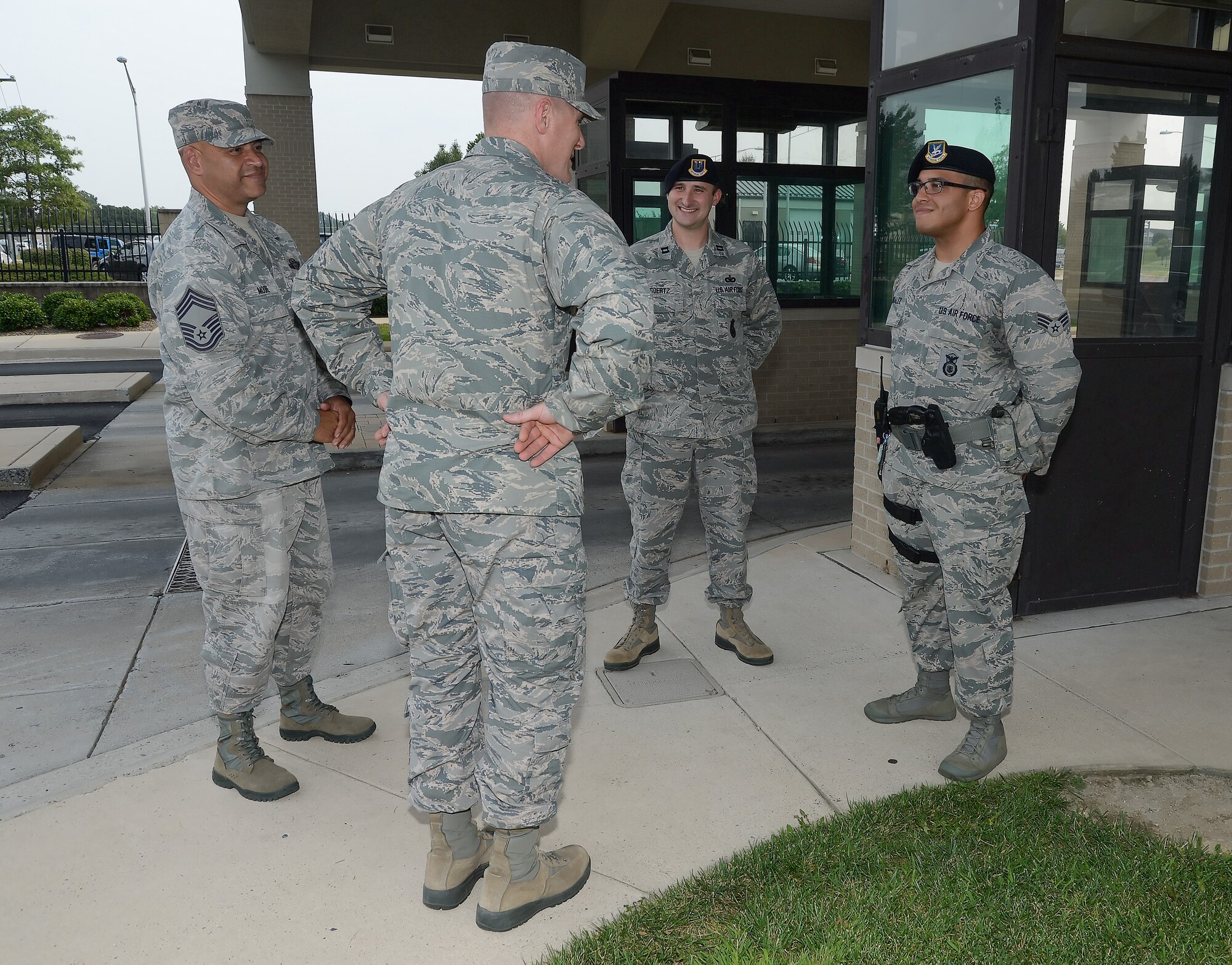 Col. Michael Grismer, 436th Airlift Wing commander, middle, talks with Senior Airman Joaquin Gonzalez, 436th Security Forces Squadron, near the in-bound lanes of traffic at the main gate Sept. 2, 2015, at Dover Air Force Base, Del. Looking on are Chief Master Sgt. Geraldo Moore, acting 436th Airlift Wing command chief,  and Capt. Christopher Goertz, 436th SFS operations officer, as they discuss the many positive impressions Gonzales has made during his interactions with personnel entering the base. (U.S. Air Force photo/Greg L. Davis)