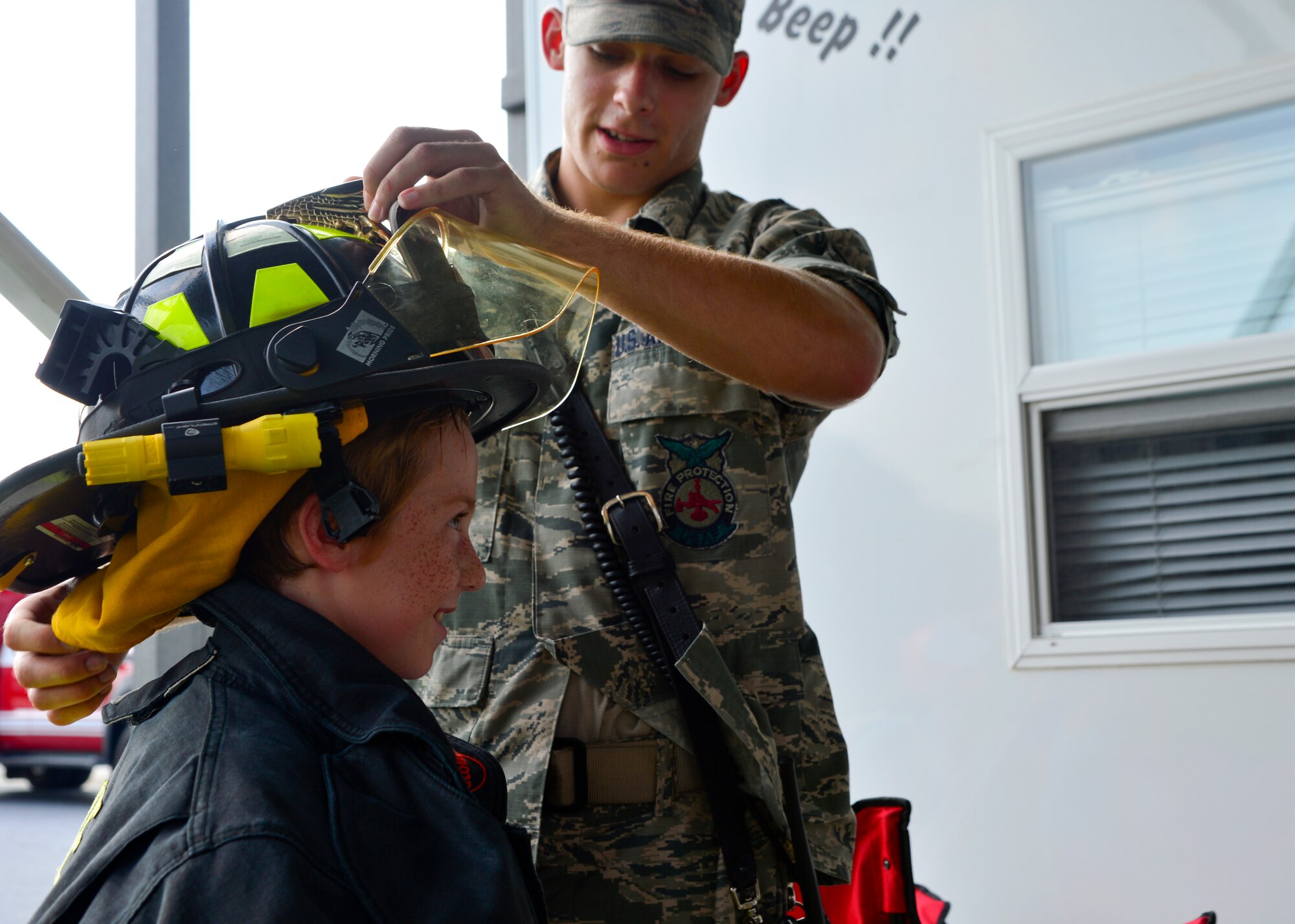 Airman 1st Class Kyle Spence, 436th Civil Engineer Squadron firefighter, dresses Skylar Knight, son of Staff Sgt. Kevin Knight, 9th Airlift Squadron flight engineer, in bunker gear during the Emergency Management Block Party Sept. 3, 2015, on base housing at Dover Air Force Base, Del. Children were able to interact with first responders and learn about emergency preparedness and how to react during real life emergencies. (U.S. Air Force photo/Airman 1st Class William Johnson)