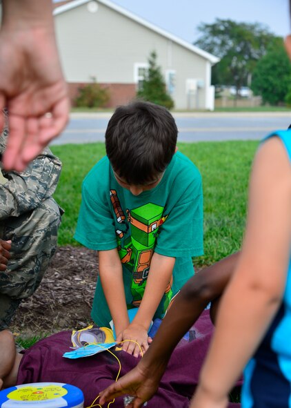 Kyle Struss, son of Staff Sgt. Danielle Struss, Armed Forces Medical Examiner System forensic toxicology technician, performs CPR on a training dummy during the Emergency Management Block Party Sept 3, 2015, on base housing at Dover Air Force Base, Del. September is National Preparedness Month and Team Dover families were able to learn first-aid care from the 436th Medical Operations Squadron at the party. (U.S. Air Force photo/Airman 1st Class William Johnson)