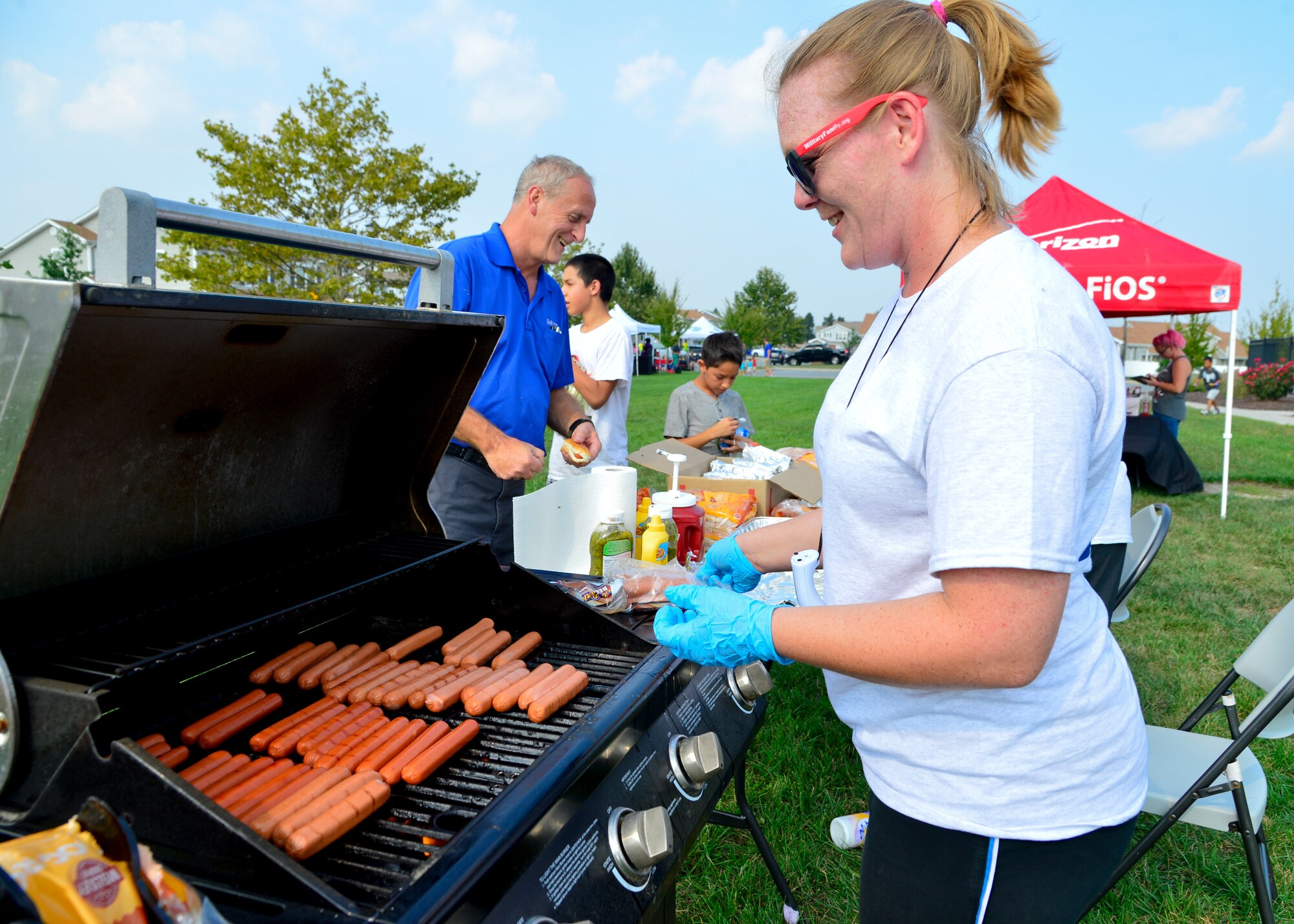 Andrea Beegle, Hunt Military Community leasing agent, grills hotdogs during the Emergency Management Block Party Sept. 3, 2015, on base housing at Dover Air Force Base, Del. The block party included fire truck tours, military working dog demonstrations, informational booth games and prize giveaways all associated with National Preparedness Month. (U.S. Air Force photo/Airman 1st Class William Johnson)