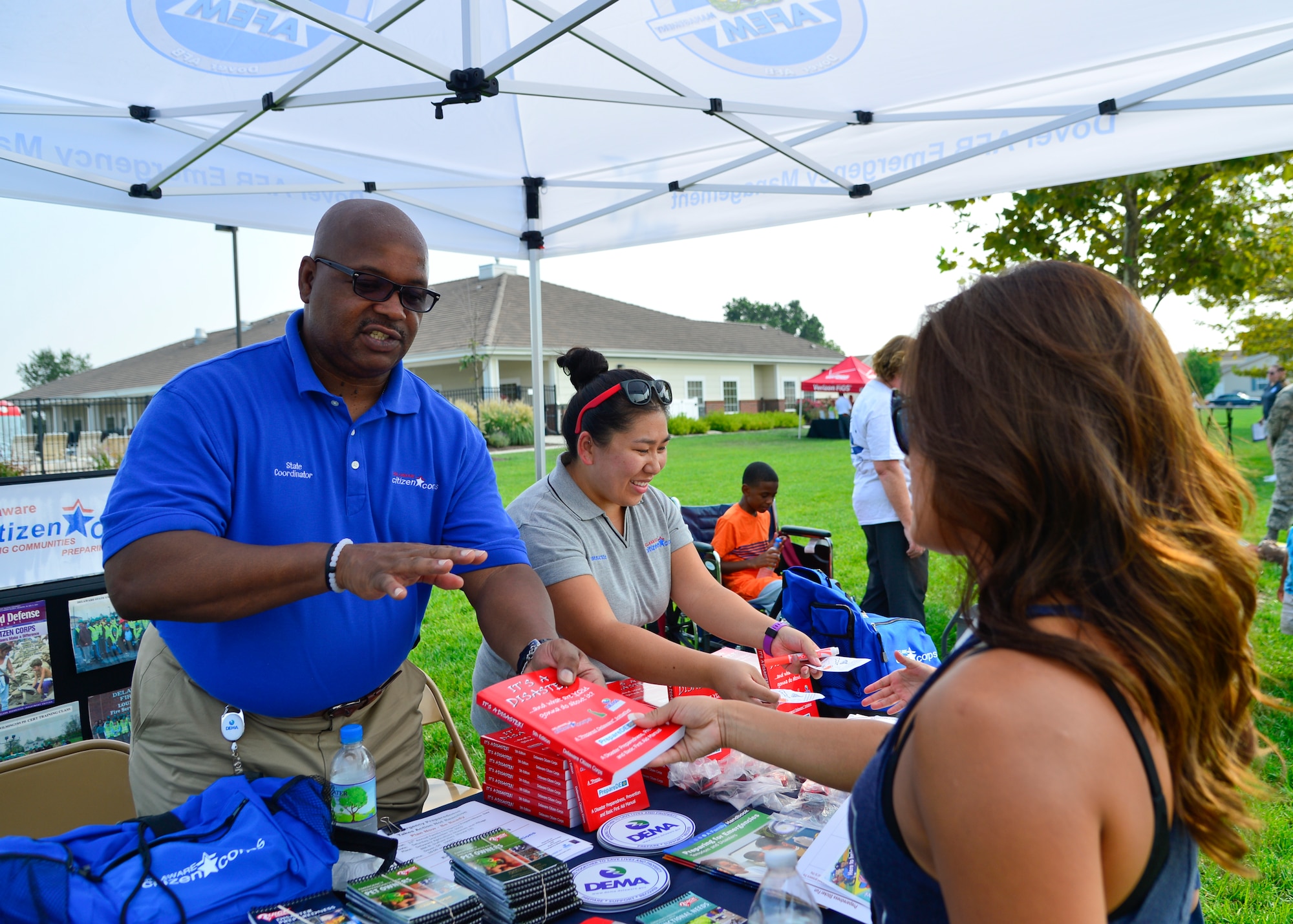 Marny McLee, Delaware Emergency Management Agency Citizen Crop Program manager, hands out emergency preparedness books during the Emergency Management Block Party Sept. 3, 2015, on base housing at Dover Air Force Base, Del. The Citizen Corp Program develops community action plans, assesses possible threats and identifies local resources during emergency situations. (U.S. Air Force photo/Airman 1st Class William Johnson)