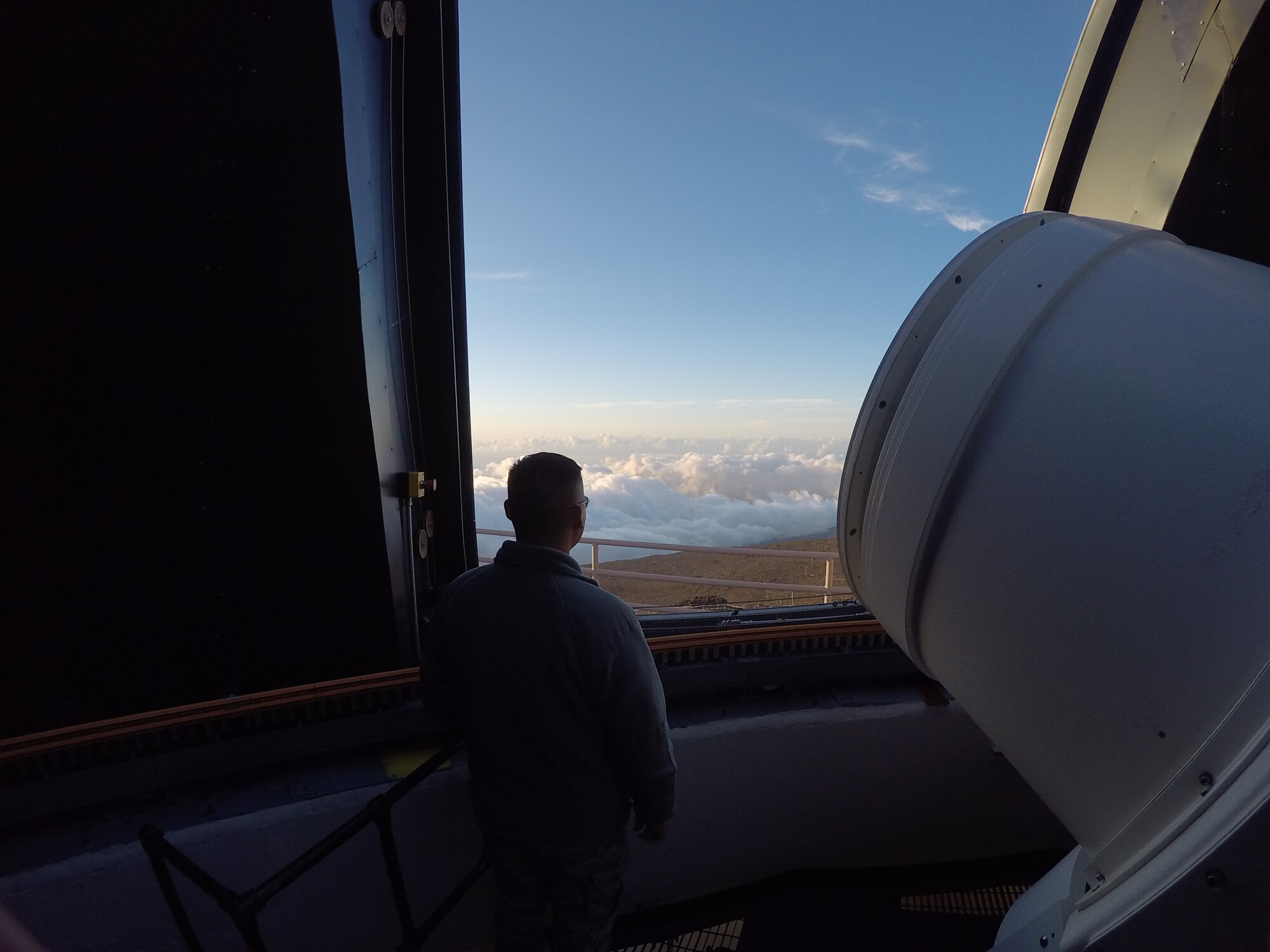 Capt. Robert Copley, commander Detachment 3, 21st Operations Group, looks out from the dome of one of the telescopes atop Haleakala volcano in Maui, Hawaii. The detachment sits on the rim of the volcano’s crater high above the cloud layer, light pollution and atmospheric interference that could impair the optical telescope’s view of deep space. 