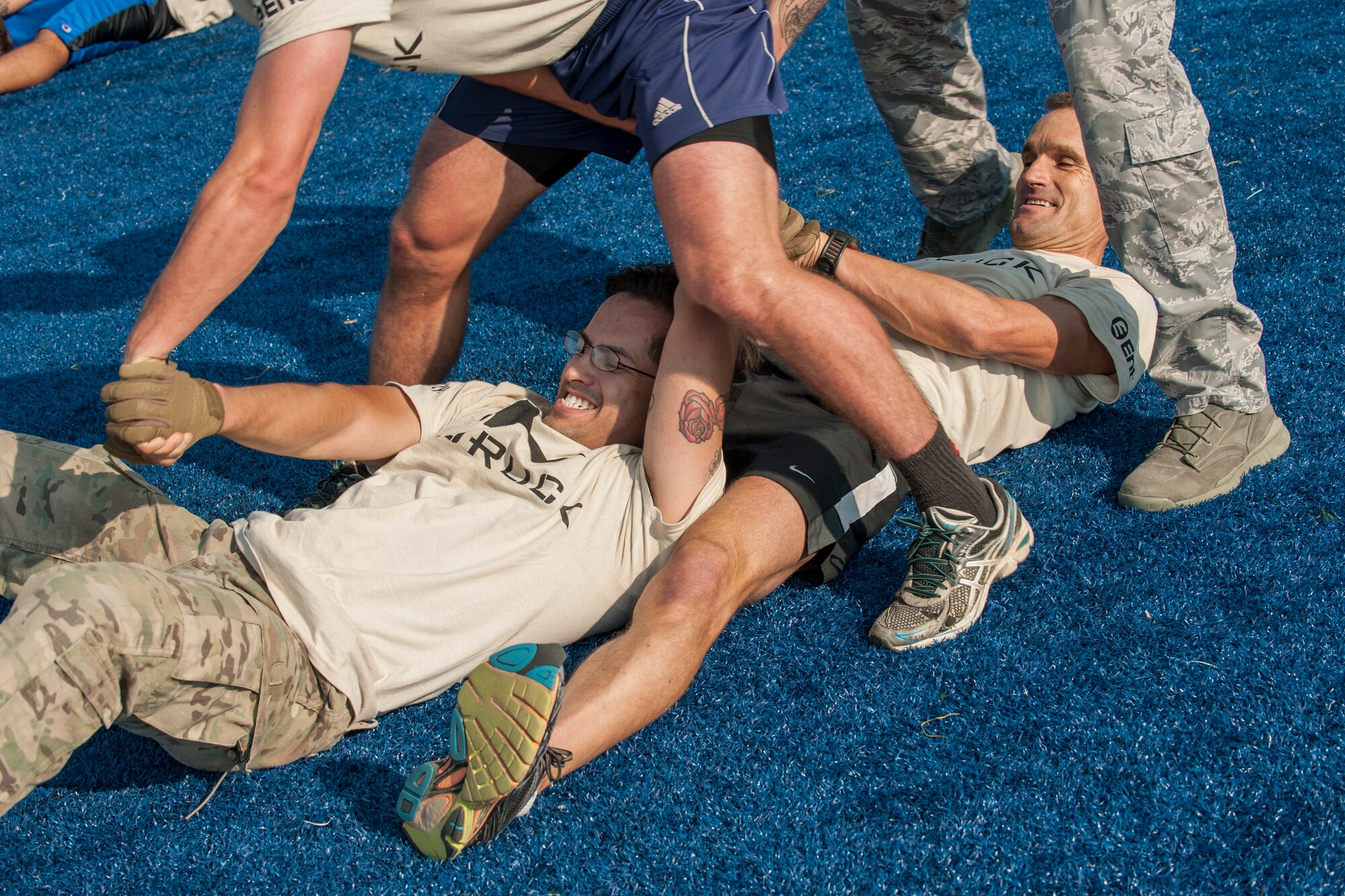 PETERSON AIR FORCE BASE, Colo. – Tech. Sgt. Robert Montano, 16 Space Control Squadron intelligence specialist, and Lt. Col. Richard Sumrall, 21st Aeromedical Squadron flight surgeon, work with their teammates to complete the “elephant roll” as part of the Team Cohesion Challenge at the base Fitness Center, Aug. 29, 2015. The challenges require teammates to work together to complete them, exhausting them physically and mentally. The event was held at Peterson for the first time and will be coming back next year for even more fun and team-building. (U.S. Air Force photo by Airman 1st Class Rose Gudex)