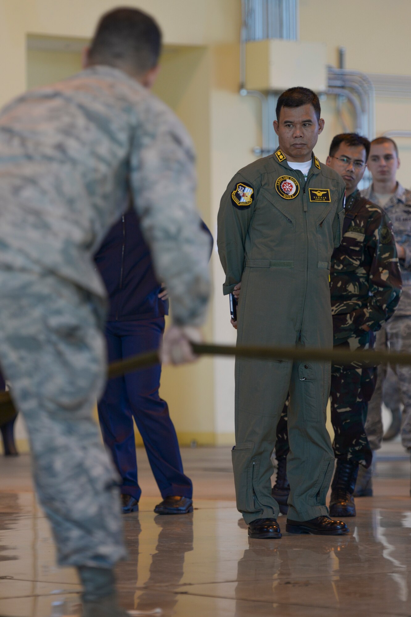 A participant with the Indonesian Air Force watches a parachute inspection during the 2015 Pacific Agility Logistics and Safety Symposium at Yokota Air Base, Japan, Sept. 2, 2015. The symposium is a Pacific Command initiative aimed at increasing interoperability between regional partners. It allowed the multinational participants to discuss and learn innovative safety, supply and maintenance standards. (U.S. Air Force photo by Staff Sgt. Cody H. Ramirez/Released)