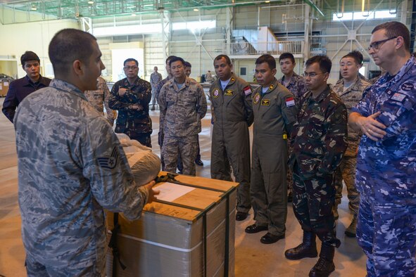 Multinational participants listen to a briefing about a low-cost, low-altitude bundle during the 2015 Pacific Agility Logistics and Safety Symposium at Yokota Air Base, Japan, Sept. 2, 2015. The symposium is a Pacific Command initiative aimed at increasing interoperability between regional partners. It allowed the multinational participants to discuss and learn innovative safety, supply and maintenance standards. (U.S. Air Force photo by Staff Sgt. Cody H. Ramirez/Released)