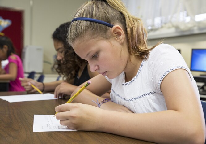 Payton Hoskins, a fifth grade student of Matthew C. Perry Elementary School, completes her school work on the first day of the new school year aboard Marine Corps Air Station Iwakuni, Japan, Aug. 31, 2015. The principle of M. C. Perry Elementary holds students to a high standard and has three main goals for success this year; take risks, take responsibility and take care of each other.