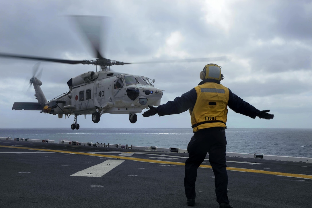 U.S. Navy Petty Officer 3rd Class Kenny Ngo signals to an SH-60 helicopter attached to the Japan Maritime Self-Defense Force on the flight deck of the amphibious assault ship USS Boxer during Dawn Blitz 2015 in the Pacific Ocean, Sept. 4, 2015. Ngo is an aviation boatswain’s mate (handling). U.S. Navy photo by Petty Officer 3rd Class Jesse Monford