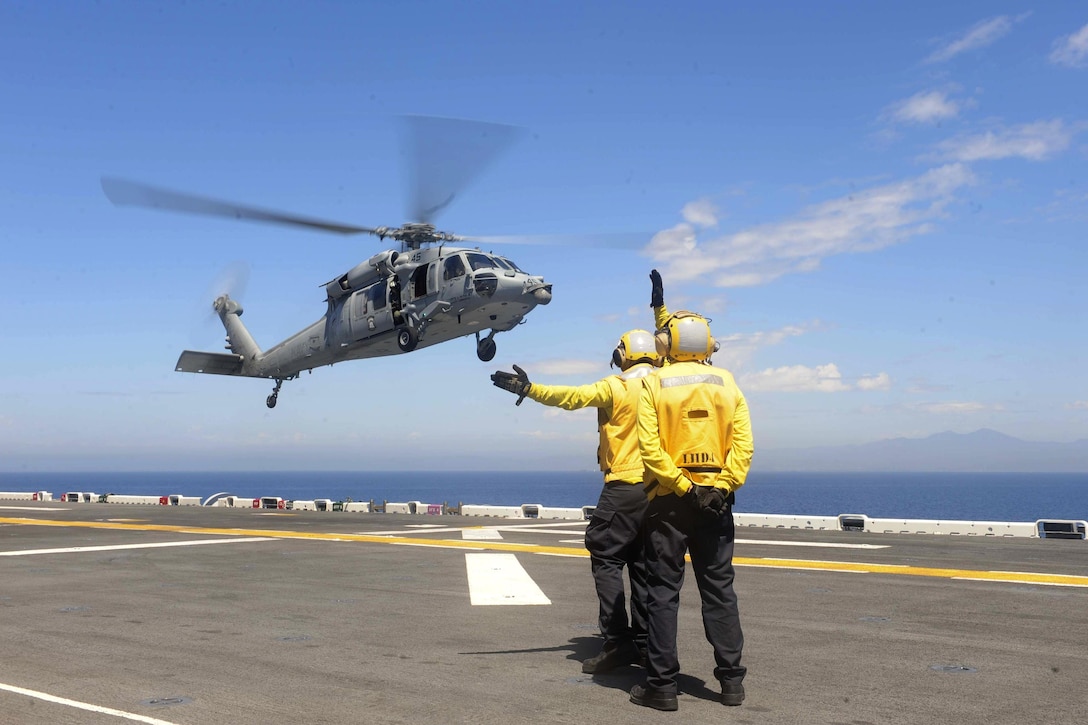 A sailor signals to an MH-60S Seahawk helicopter on the flight deck of the amphibious assault ship USS Boxer during Dawn Blitz 2015 in the Pacific Ocean, Sept. 6, 2015. The sailor is an aviation boatswain’s mate (handling). The Seahawk is assigned to Helicopter Sea Combat Squadron 23. U.S. Navy photo by Petty Officer 2nd Class Jose Jaen