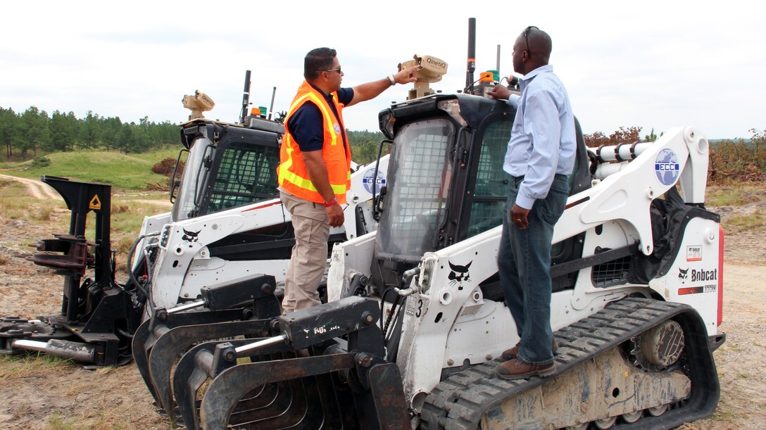 Ray Velazquez (left), ECC senior project manager, describes operation of a "MOOG" Pan/Tilt/Zoom Thermal and Visible Imaging System to Spencer O’Neal, U.S. Army Engineering and Support Center, Huntsville vegetation clearance project manager.  The "MOOG" is a camera mounted on the "robots" used for vegetation removal project at Fort Bragg, North Carolina. The camera allows for daylight and night time operations.  