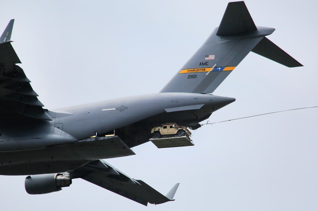 A C-17 Globemaster III drops a Humvee vehicle fitted with a parachute system during Pacific Airlift Rally 2015 over Malemute drop zone on Joint Base Elmendorf-Richardson, Alaska, Aug. 27, 2015. The air crew is assigned to the Alaska Air National Guard's 249th Airlift Squadron. U.S. Air Force photo by Alejandro Pena