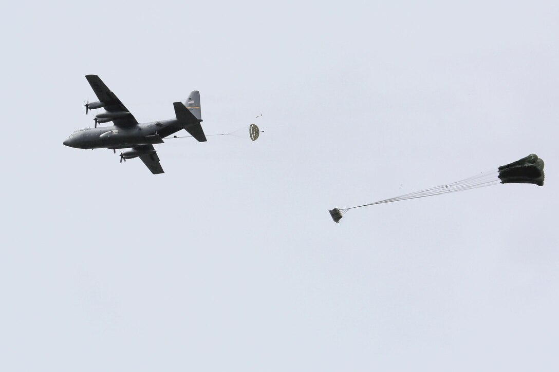 A C-130 Hercules aircraft drops a load of palletized equipment fitted with a parachute system during Pacific Airlift Rally 2015 over Malemute drop zone on Joint Base Elmendorf-Richardson, Alaska, Aug. 27, 2015. The air crew is assigned to the Alaska Air National Guard's 249th Airlift Squadron. U.S. Air Force photo by Alejandro Pena