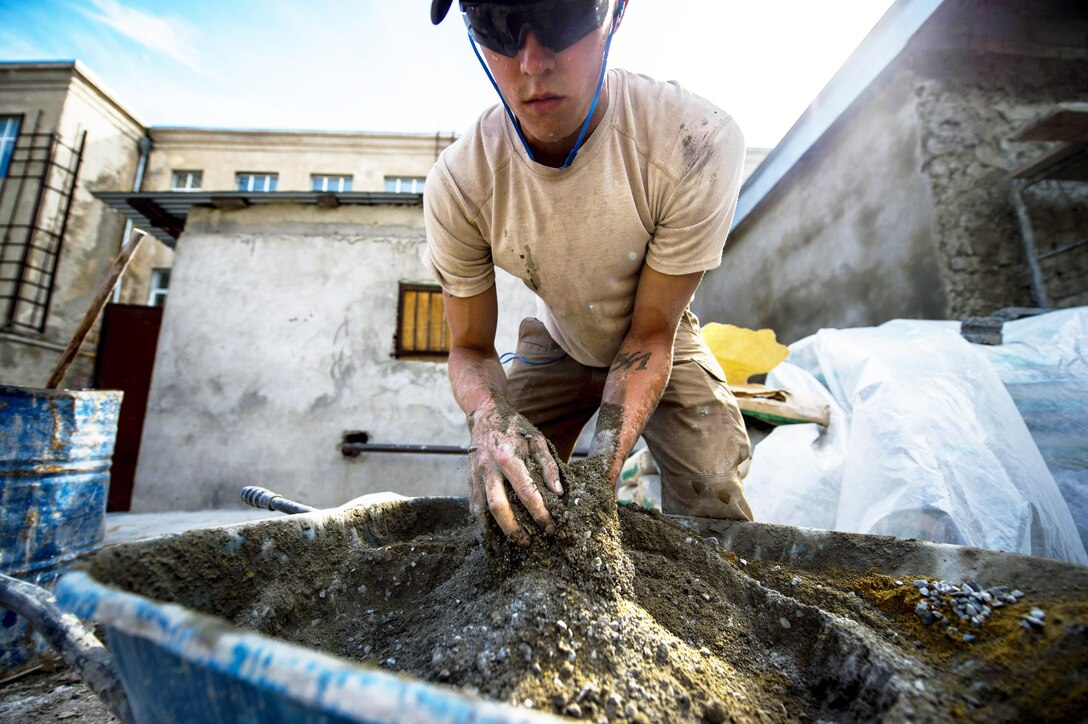 U.S. Air Force Airman 1st Class Cole Kasten mixes cement for a ramp at a public school Gori, Georgia, Aug. 28, 2015. Kasten, a pavement and heavy equipment operator with the 52nd Civil Engineer Squadron, and fellow airmen built the ramp to give disabled students safe access into the gymnasium. U.S. Air Force photo by Staff Sgt. Sara Keller