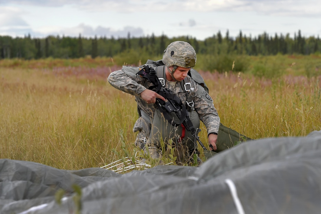 Army Spc. Chase Guenther gathers his equipment after conducting a practice jump during Pacific Airlift Rally 2015 over Malemute drop zone on Joint Base Elmendorf-Richardson, Alaska, Aug. 27, 2015. Guenther is assigned to the 25th Infantry Division's Headquarters Battery, 2nd Battalion, 377th Parachute Field Artillery Regiment, 4th Infantry Brigade Combat Team, Alaska. U.S. Air Force photo by Alejandro Pena