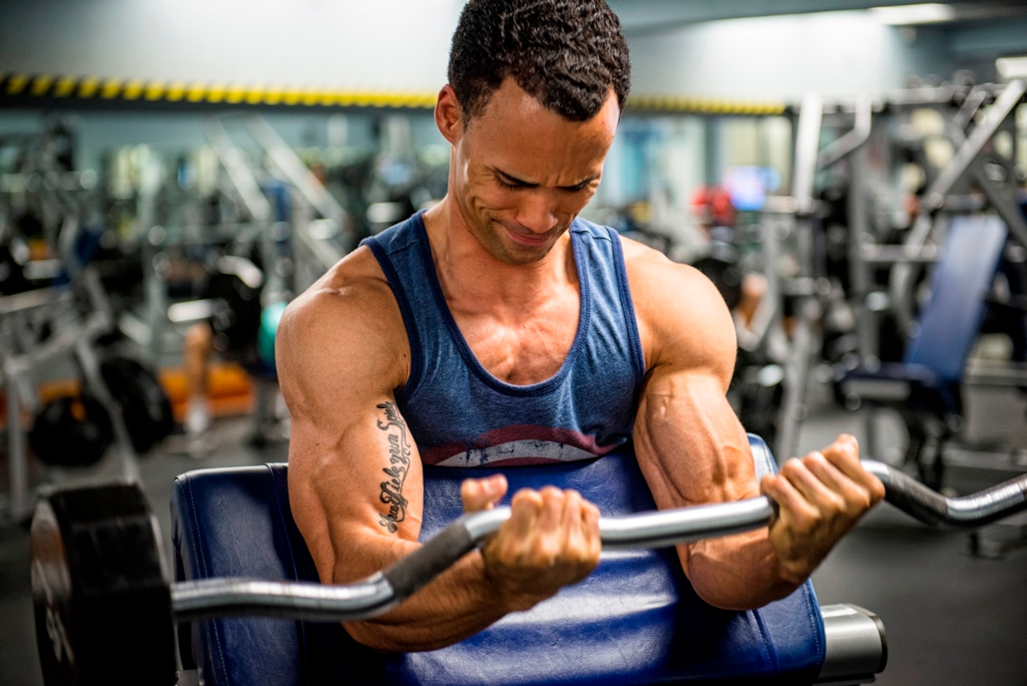 First Lt. Roman Tillman, a 5th Space Launch Squadron responsible engineer, 120-pounds on the curl bar July 21, 2015, at the fitness center on Patrick Air Force Base, Fla. Tillman is a men’s physique competitor who won first place in the first two competitions he entered. (U.S. Air Force photo/Matthew Jurgens)