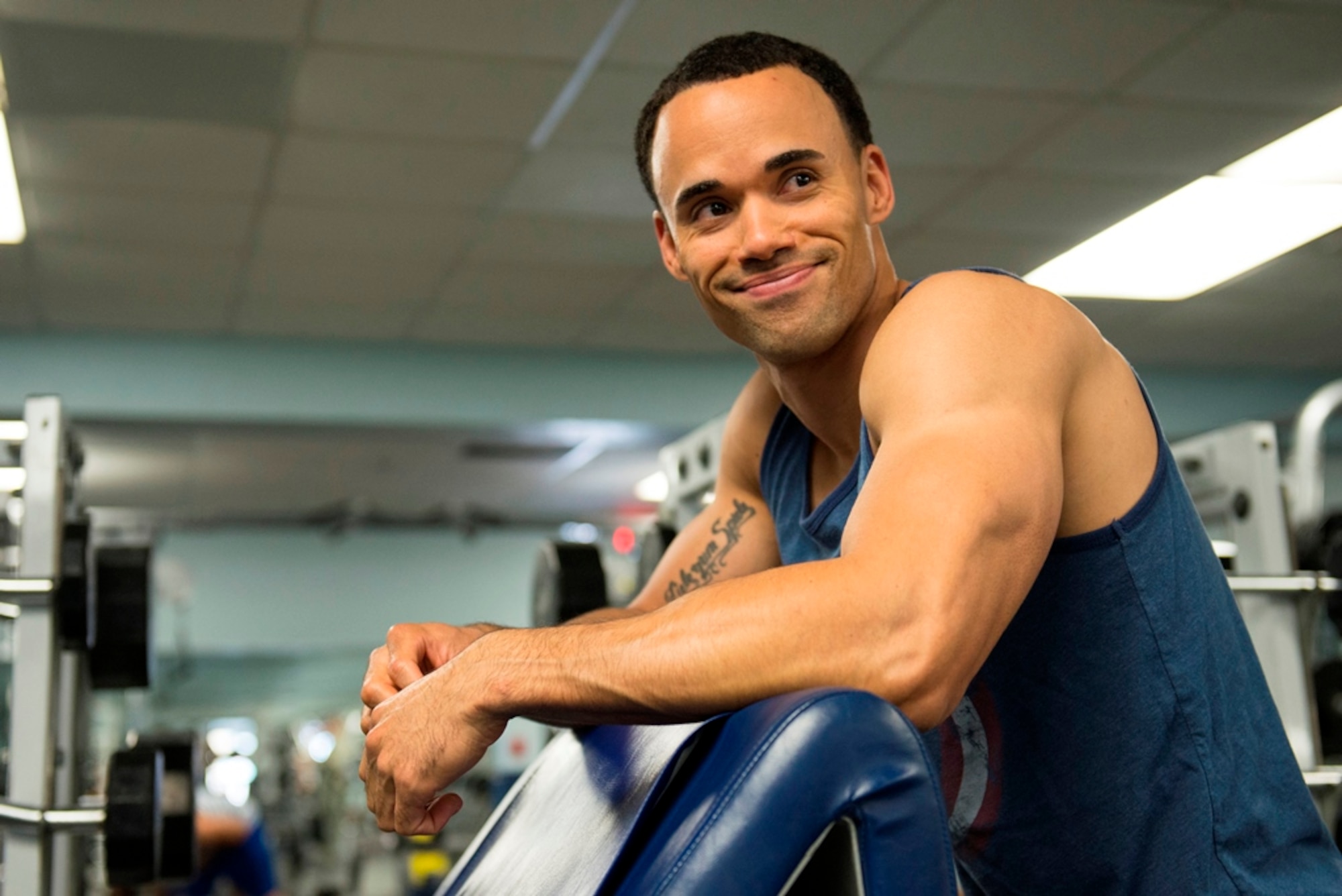 First Lt. Roman Tillman, a 5th Space Launch Squadron responsible engineer, takes a break before performing more repetitions in his workout routine July 21, 2015, at the fitness center on Patrick Air Force Base, Fla. Tillman is a men’s physique competitor working toward his International Federation of Bodybuilding and Fitness pro card. (U.S. Air Force photo/Matthew Jurgens)