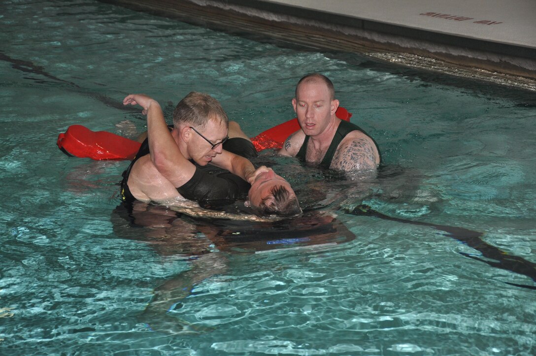 Sgt. Marshall Breaugh, L, instructor trainer, 2nd Lt. Ward Scott, student at The Basic School from Plymouth, N.H., and Sgt. David Labell, instructor trainer, conduct annual water survival training at Ramer Hall Gymnasium, Aug. 4. The Marine Corps Instructor Trainer of Water Survival team and firemen from the Fire Station 533 at TBS collaborated in the realistic training efforts.