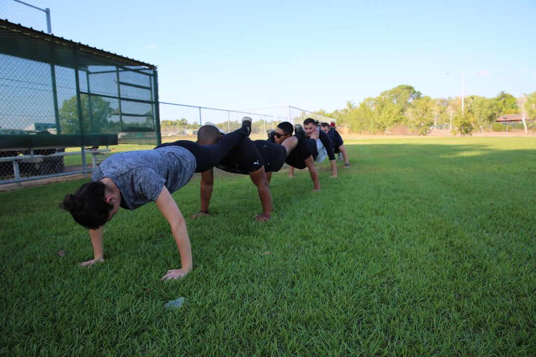 U.S. Marines with Marine Rotational Force – Darwin conduct squad pushups to demonstrate a team-building exercise during a softball clinic for local youth July 25 at Tracy Village Social and Sports Club, Wanguri, Northern Territory, Australia. The Marines supported the U.S. State Department-sponsored community event with the Northern Territory’s school softball program to mentor the students and teach them how to play competitively. Beyond purely military training, Marines’ involvement in community engagements in the Northern Territory shows their appreciation for Australia’s hospitality.