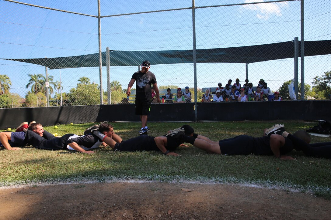 U.S. Marines with Marine Rotational Force – Darwin conduct squad push-ups to demonstrate a team-building exercise during a softball clinic for local youth July 25 at Tracy Village Social and Sports Club, Wanguri, Northern Territory, Australia. The Marines supported the U.S. State Department-sponsored community event with the Northern Territory’s school softball program to mentor the students and teach them how to play competitively. Beyond purely military training, Marines’ involvement in community engagements in the Northern Territory shows their appreciation for Australia’s hospitality. 