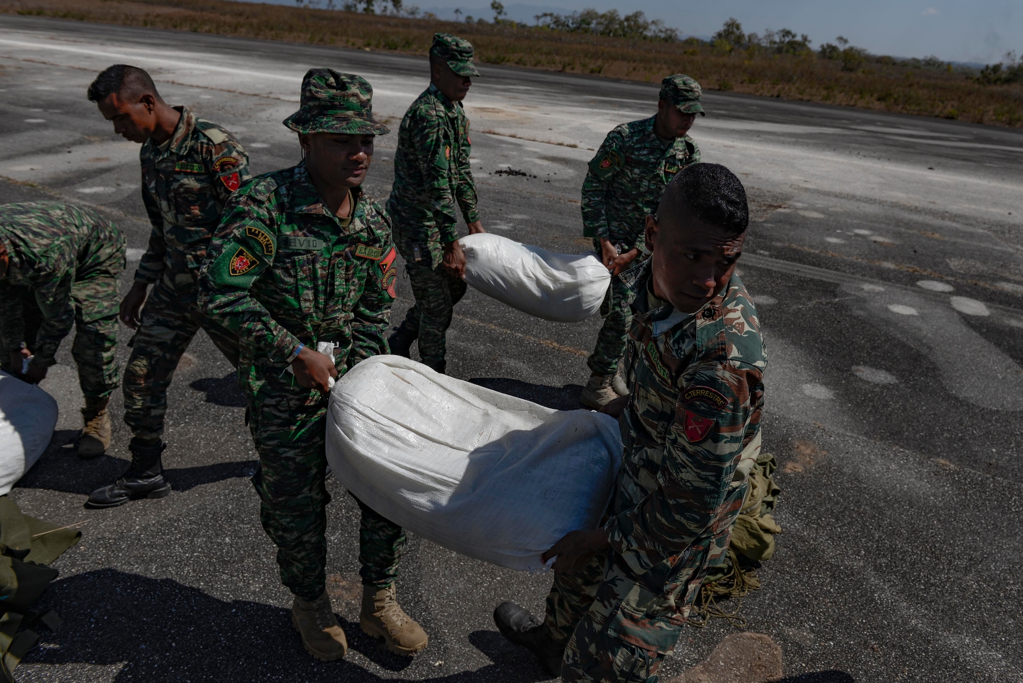 Soldiers with the Falintil Forças de Defesa de Timor-Leste carry bags of rice that were just airdropped by a U.S. Air Force C-130 Hercules over Baucau airfield, Sept. 8, 2015, in Baucau, Timor-Leste. The packages were airdropped by a North Carolina Air National Guard C-130 crew during Operation Pacific Angel 15-2. Efforts undertaken during Pacific Angel help multilateral militaries in the Pacific improve and build relationships across a wide spectrum of civic operations, which bolsters each nation’s capacity to respond and support future humanitarian assistance and disaster relief operations. (U.S. Air Force photo by Staff Sgt. Alexander W. Riedel/Released)