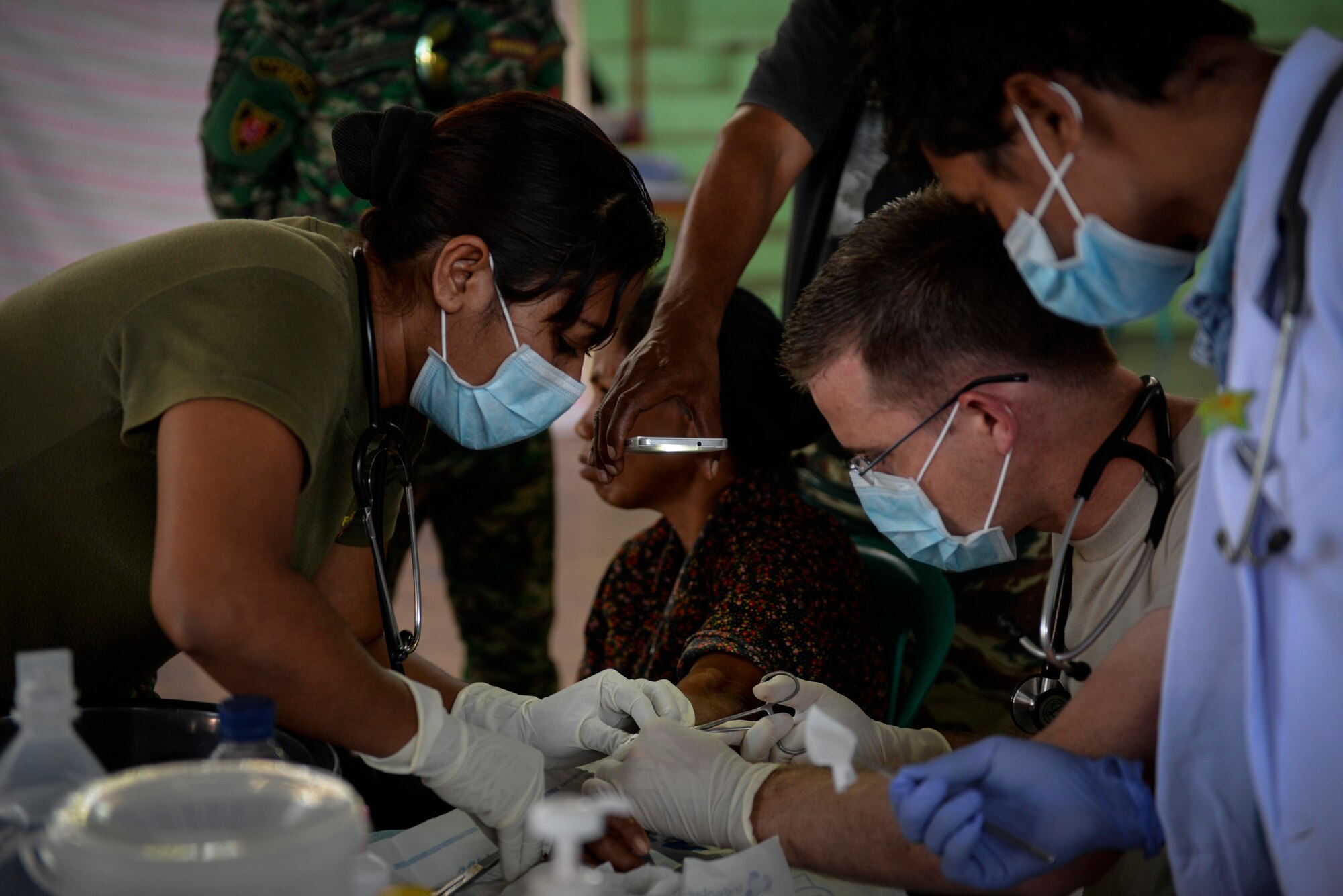 U.S. Air Force Maj. Richard Trowbridge (right), family practice physician assigned to the 374th Medical Group at Yokota Air Base, Japan, extracts a cyst from a patient's arm with Falintil-Forças de Defesa de Timor-Leste 2nd Lt. Anabela de Cruz (left), during an Operation Pacific Angel 15-2 health services outreach clinic Sept. 7, 2015, in Baucau, Timor-Leste. Pacific Angel is a multilateral humanitarian assistance civil military operation, which improves military-to-military partnerships in the Pacific while also providing medical health outreach, civic engineering projects and subject matter exchanges among partner forces. (U.S. Air Force photo by Staff Sgt. Alexander W. Riedel/Released)